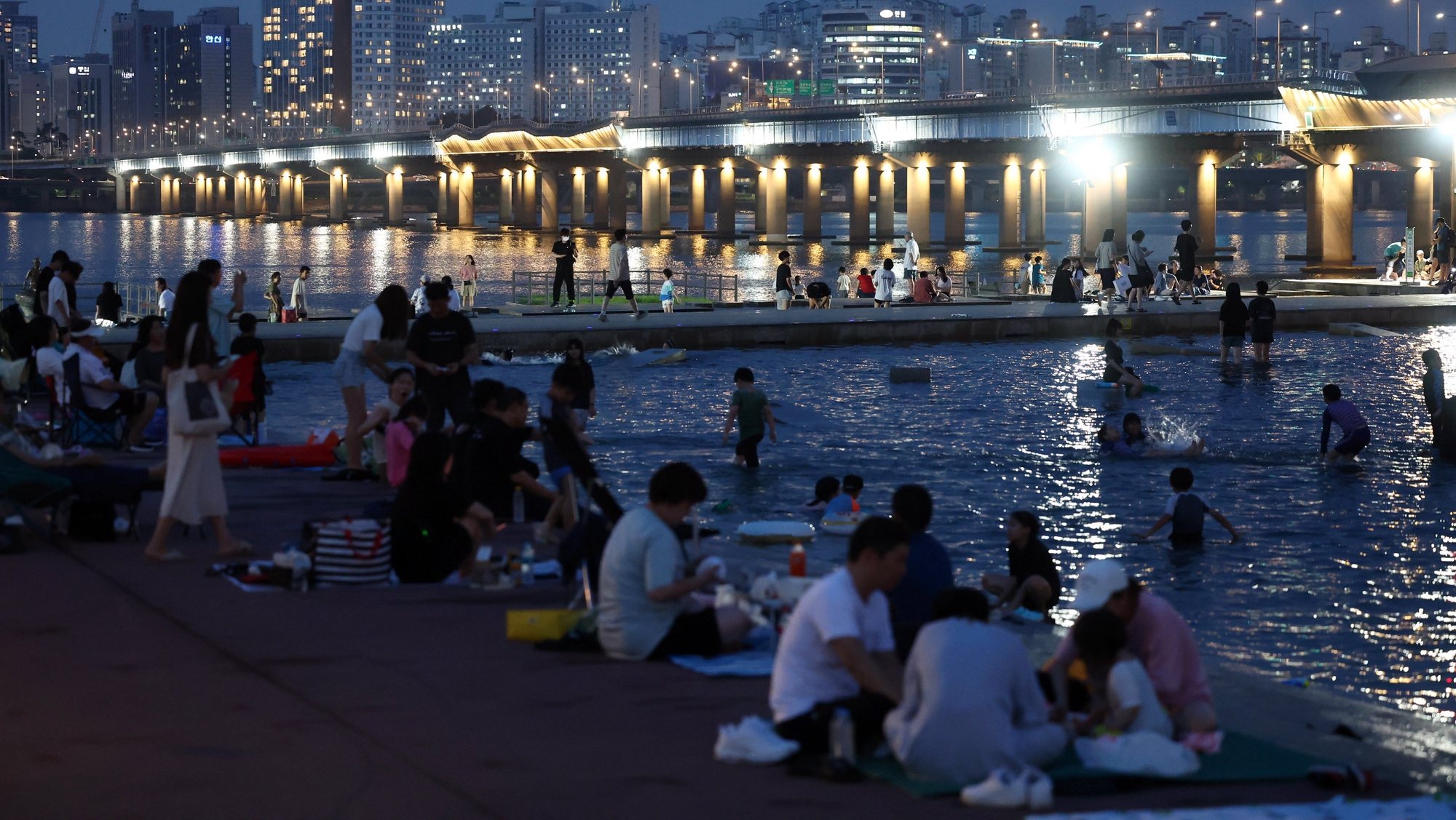 epa10778507 People cool off in a public park alongside the Han River in Seoul, South Korea, 31 July 2023, as a sweltering heat wave grips the country.  EPA/YONHAP SOUTH KOREA OUT