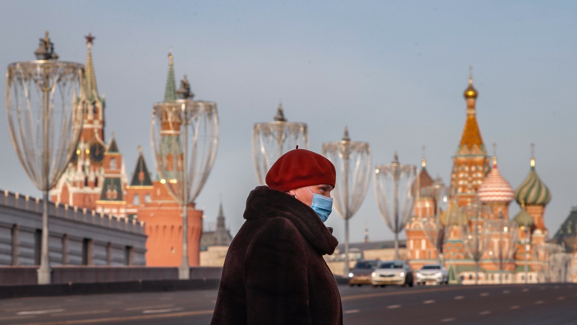 epa08877228 Russian woman wearing protective face mask walks on the street in front of Kremlin in Moscow, Russia 11 December 2020. According to official inforrmation, 613 people infected with coronavirus passed away on 11 December in Russia.  EPA/YURI KOCHETKOV