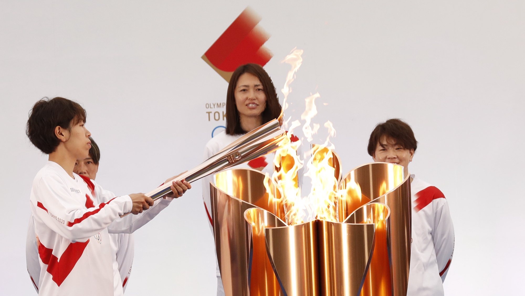 epa09095217 The Olympic torch is lit by a member of Japan&#039;s women&#039;s national soccer team Nadeshiko Japan during the Tokyo 2020 Olympic Torch Relay Grand Start in Naraha, Fukushima prefecture, Japan, 25 March 2021. The postponed Tokyo 2020 Olympic Games are scheduled to start on 23 July 2021 and some 10,000 torchbearers will run across the country along a 121-day journey.  EPA/KIM KYUNG-HOON / POOL
