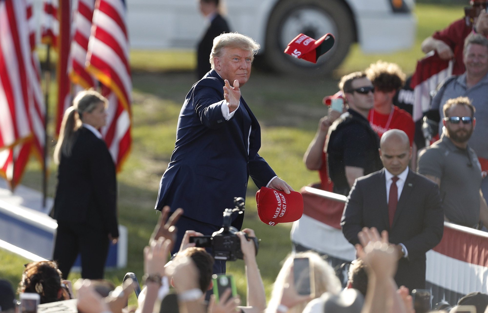 epa09905591 Former US President Donald Trump tosses MAGA hats to the crowd as he arrives for a Save America rally at the Delaware County Fairgrounds in Delaware, Ohio, USA, 23 April 2022.  EPA/DAVID MAXWELL