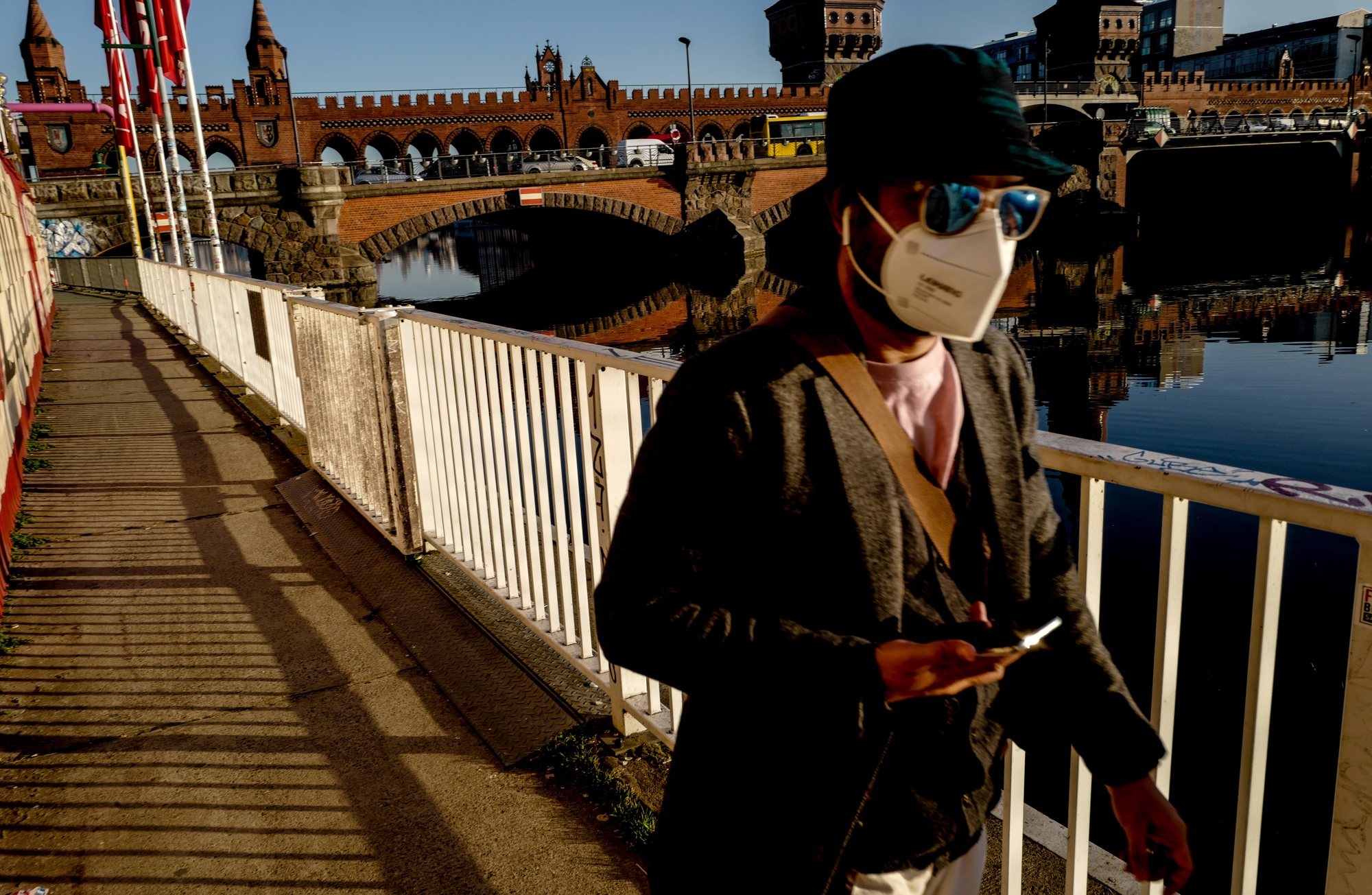 epa09047111 A man wears mask as walks next to Oberbaum Bridge in Berlin, Germany, 02 March 2021. People in Berlin took the sunny weather with spring-like warm temperatures as an opportunity to go outside during lockdown and to sit in the sun, to run or to stroll. The German Chancellor meets on 03 March the heads of the German regional states at the chancellery to discuss further lockdown measures due to the COVID-19 disease crisis caused by the SARS-CoV-2 coronavirus.  EPA/FILIP SINGER