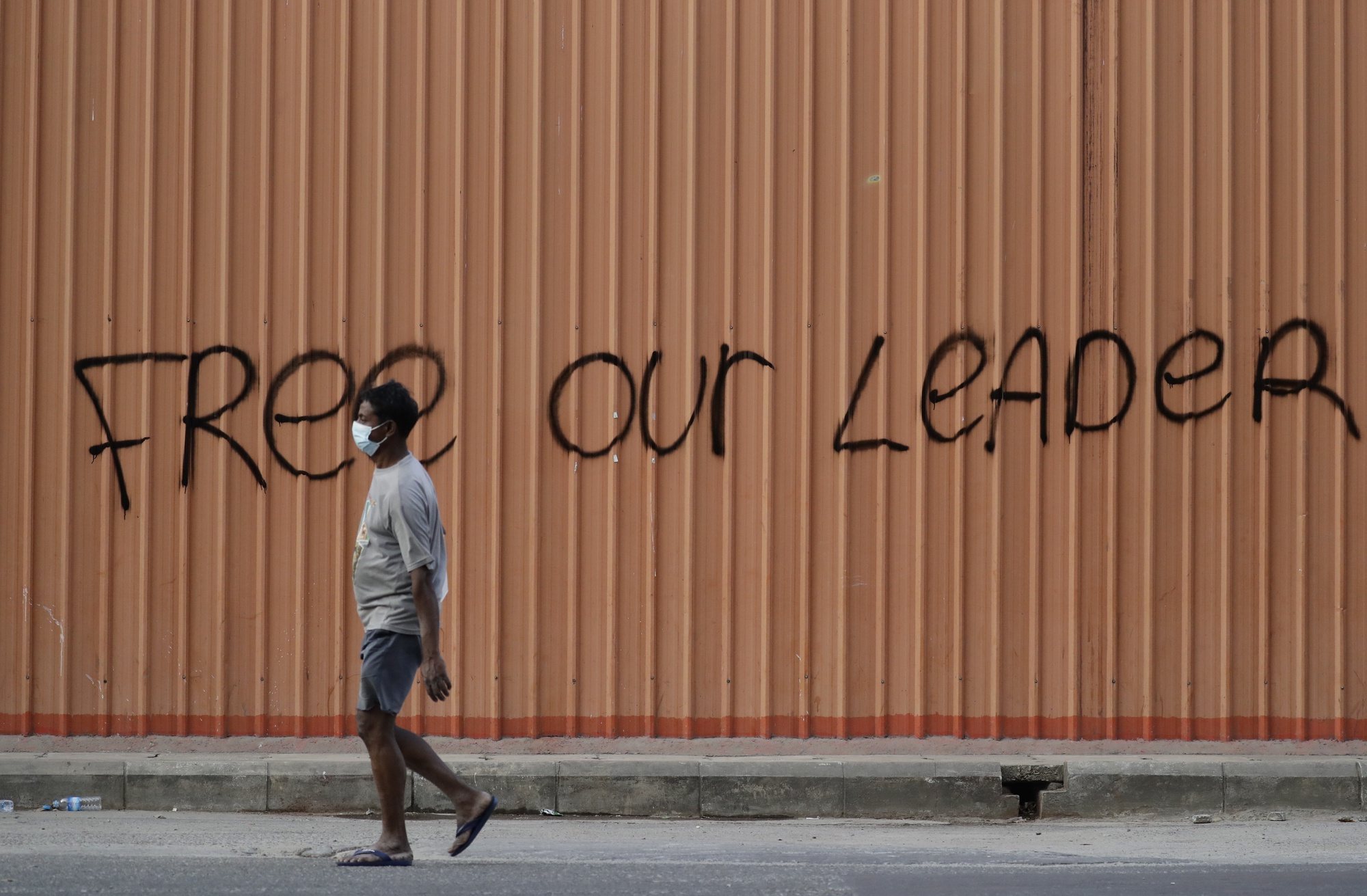 epa08996371 A man walks past a wall sprayed with the words &#039;Free Our Leader&#039; in the downtown area of Yangon, Myanmar, 08 February 2021. Thousands of people across Myanmar took to the streets for a third day of mass protests against the military coup. Myanmar&#039;s military seized power and declared a state of emergency for one year after arresting State Counselor Aung San Suu Kyi and Myanmar president Win Myint in an early morning raid on 01 February.  EPA/LYNN BO BO