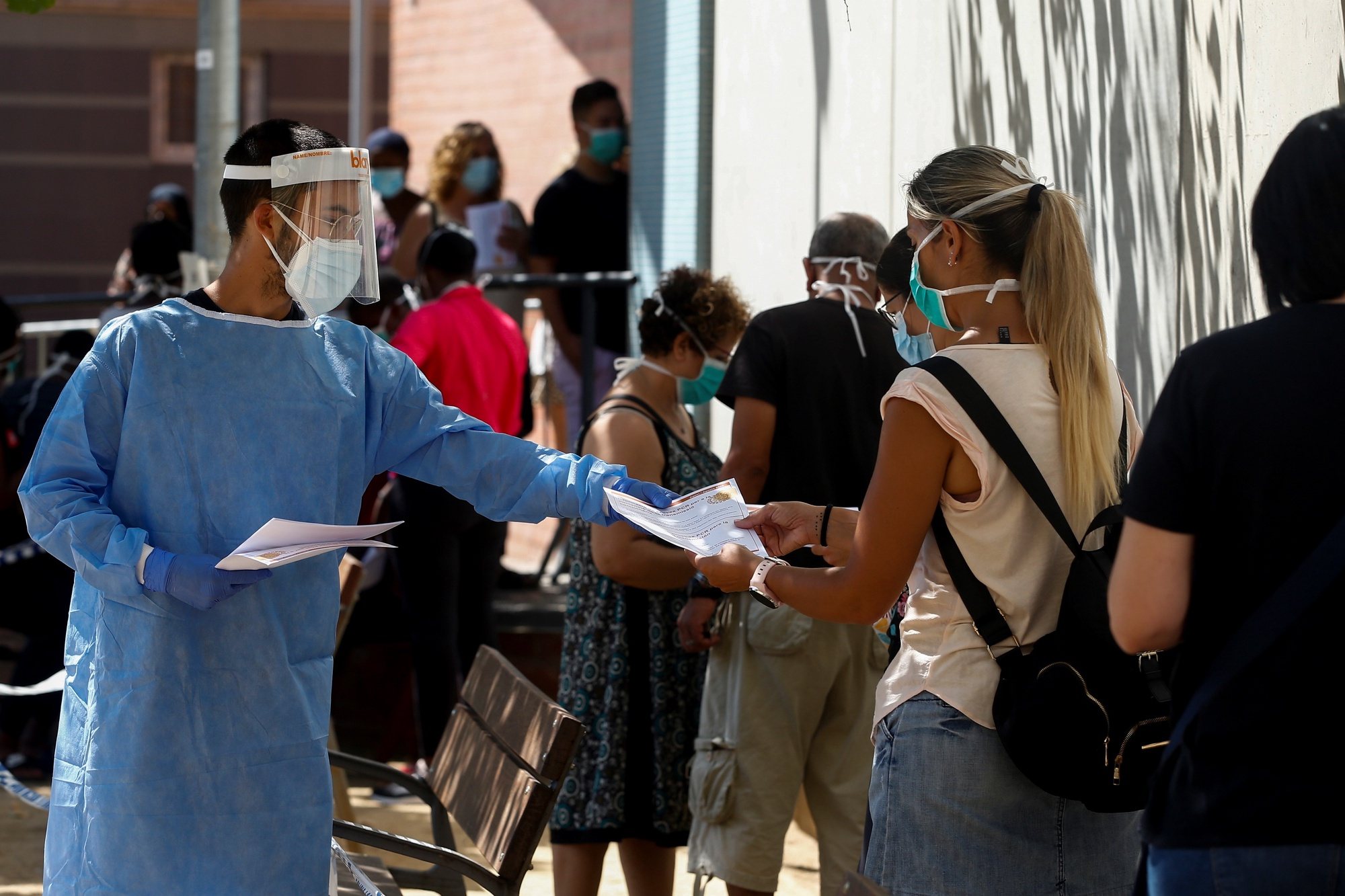 epa08624520 A health worker informs people queuing at a Health Center in Canovellas, Barcelona, Spain, where a massive PCR screening test is being carried out 25 August 2020, in order to detect asymptomatic COVID-19 cases.  EPA/Quique Garcia