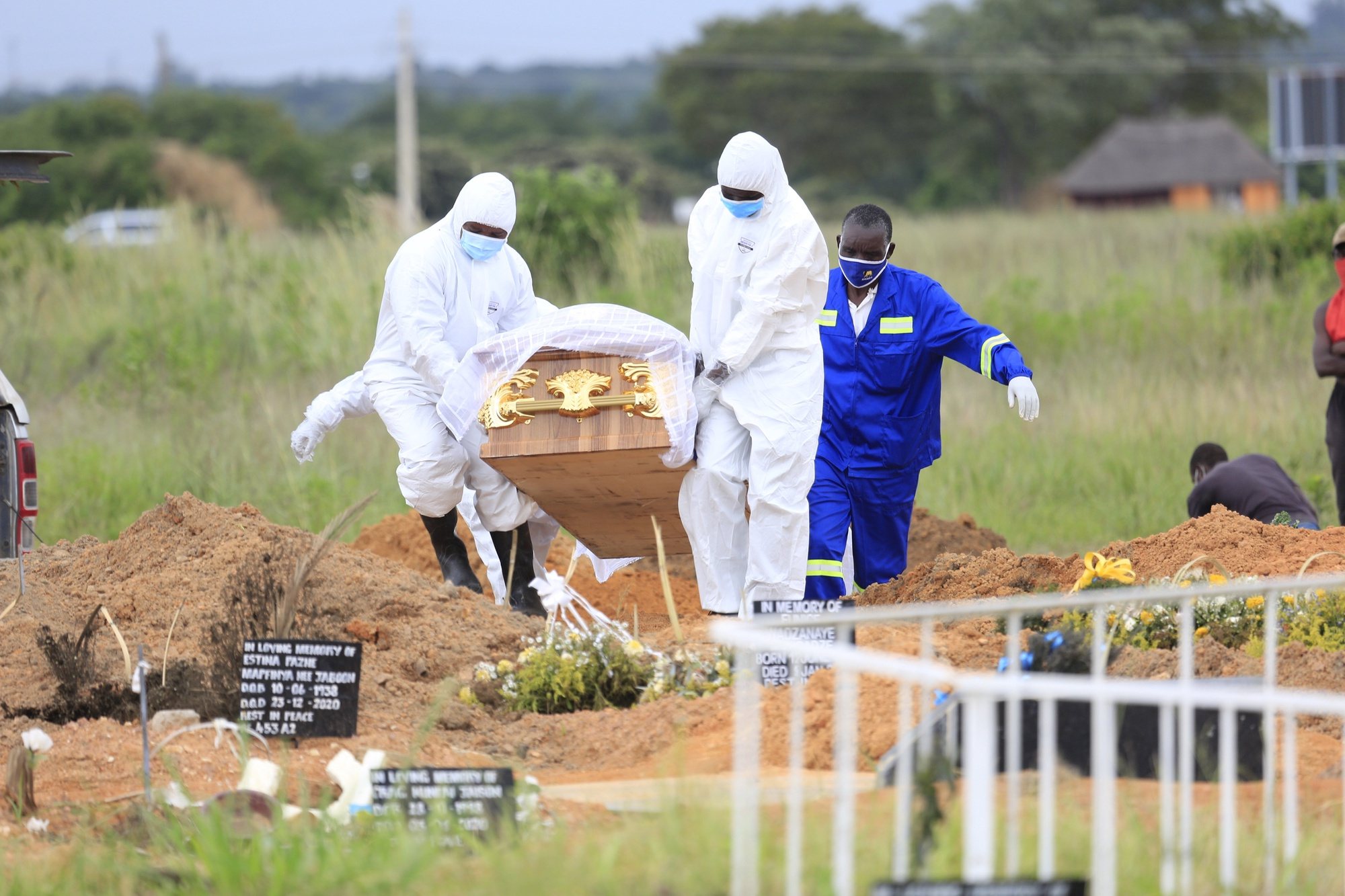 epa08946394 Funeral parlour workers wearing protective gear carry a casket to the grave of  a covid -19 victim at Zororo Memorial Park, in Chitungwiza, Zimbabwe, 18 January 2021. The country has seen an increase in the number of coronavirus related deaths with an average of 250 fatalities per week since December 2020.











.  EPA/AARON UFUMELI