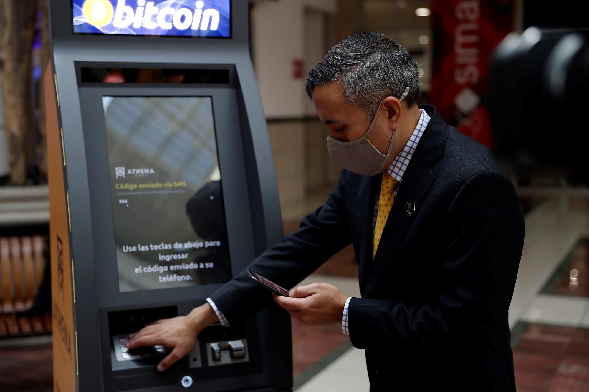 epa09299465 Eric Gravengaard, CEO and founder of the Anthena Bitcoin company, performs an operation at the new ATM for bitcoin transactions, in a shopping center in San Salvador, El Salvador, 24 June 2021. The US company Athena Bitcoin began the process of installing ATMs in El Salvador to carry out different operations of the cryptocurrency bitcoin. The ATM, which is the second in the Central American country after the one installed more than a year ago in the El Zonte tourist beach, is located in a shopping center in the central department of La Libertad.  EPA/Rodrigo Sura