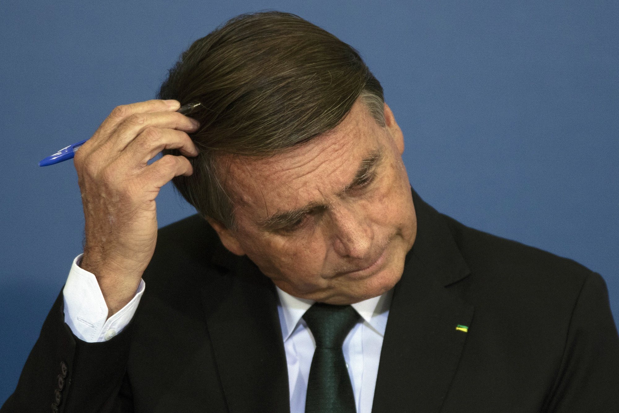 epa10024481 The President of Brazil Jair Bolsonaro, touches his head while participating in an act of National Policy for the Recovery of Learning in Basic Education, and the MECPlace, Innovation Ecosystem, and Digital Educational Solutions, at the Palacio do Planalto, in Brasilia, Brazil, 20 June 2022.  EPA/Joedson Alves