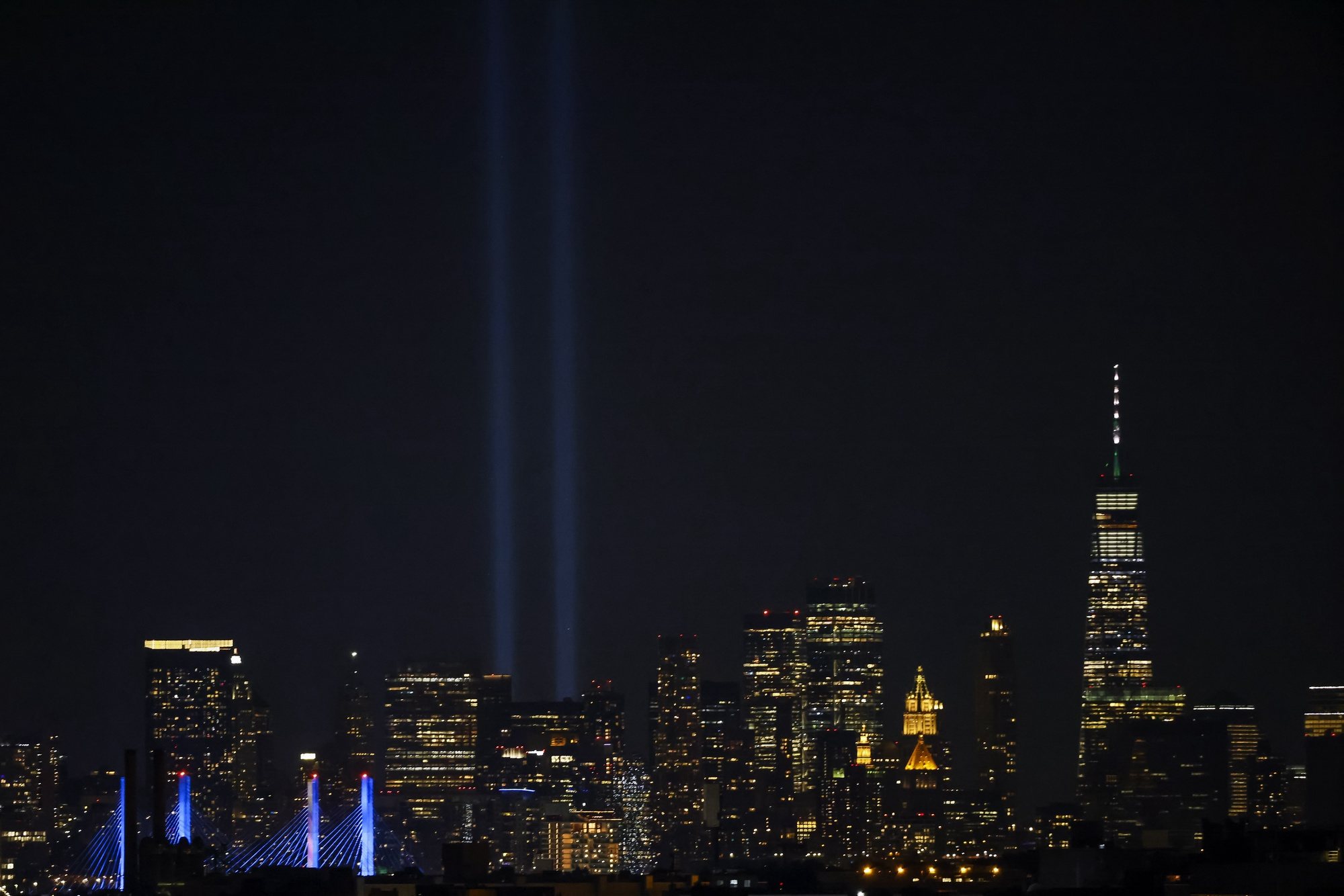 epa09460525 The Tribute in Light in downtown Manhattan, a memorial to the victims of 9/11 terrorist attacks, is seen on the eve of the 20th anniversary of the attacks, from the US Open Tennis Championships at the USTA National Tennis Center in Flushing Meadows, New York, USA, 10 September 2021.  EPA/JASON SZENES