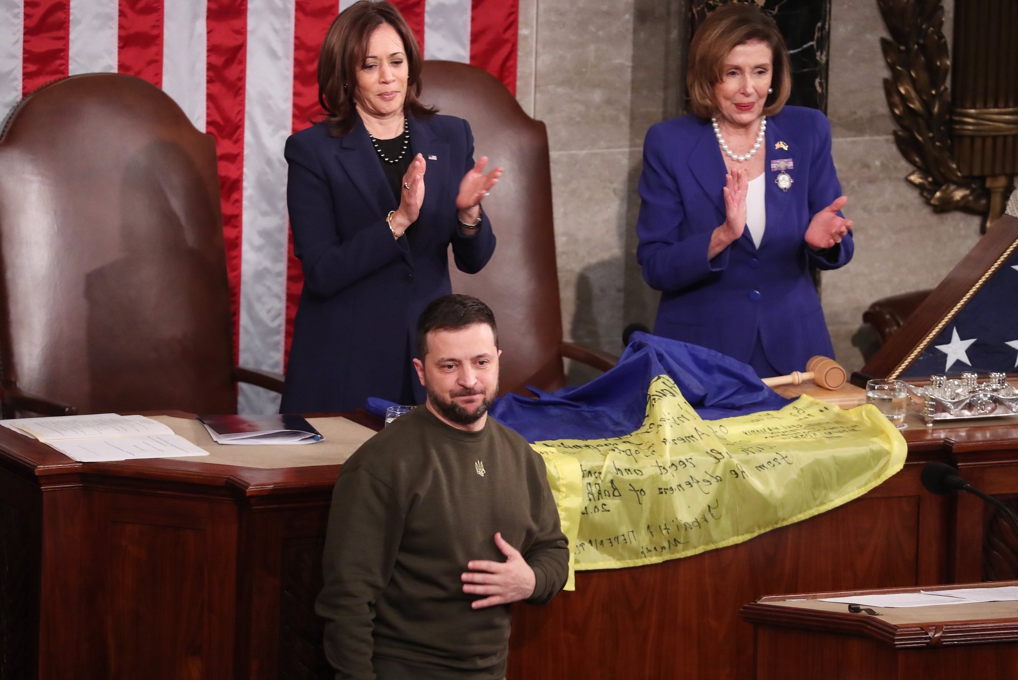 epa10376008 Speaker of the House Nancy Pelosi (C) and US Vice President Kamala Harris (L) hold a Ukrainian flag after Ukrainian President Volodymyr Zelensky  delivered an address to a joint meeting of the United States Congress in the House of Representatives chamber on Capitol Hill in Washington DC, USA, 21 December 2022. Zelensky is on his first known foreign trip since Russia invaded Ukraine more than 300 days ago, travelling to the US on a high-stakes visit to secure support for his war effort.  EPA/MICHAEL REYNOLDS