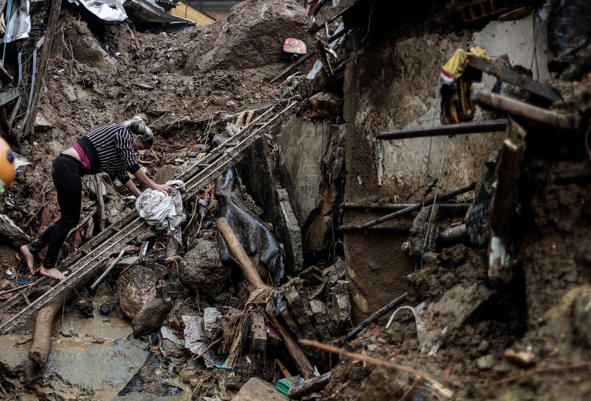 epa09763778 A woman tries to walk on the rubble left by heavy rains, in Petropolis, Brazil, 16 February 2022. Petropolis was devastated by the rains that have left more than fifty dead, thousands of homeless people and an unknown number of disappeared.  EPA/Antonio Lacerda