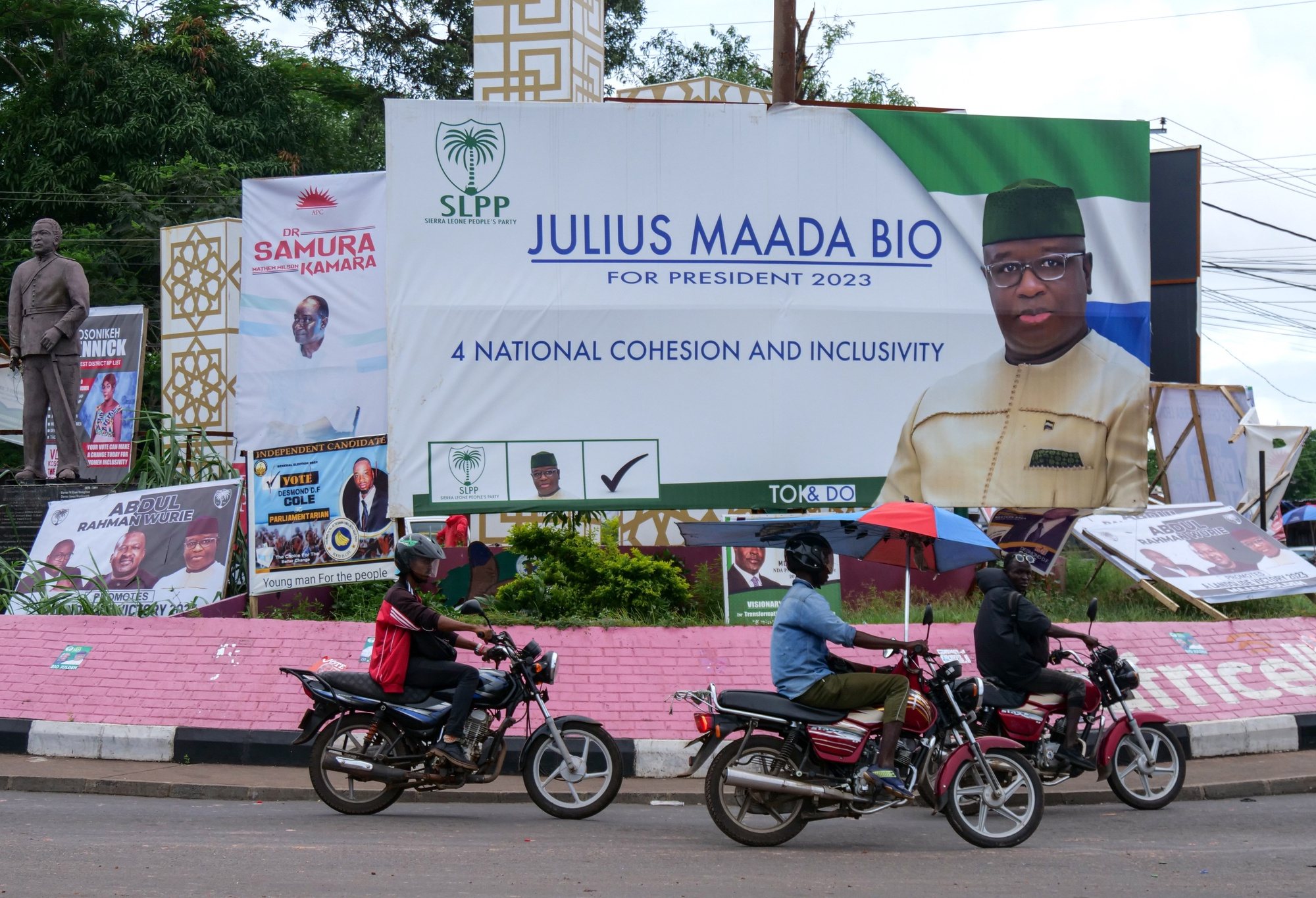 epa10708396 Motorcyclists ride past elections campaign banners in Freetown, Sierra Leone, 23 June 2023. Over three million Sierra Leoneans citizens are expected to cast their votes in a general election on 24 June 2023 in which incumbent President Julius Maada Bio is seeking a second and final term.  EPA/IBRAHIM BARRIE