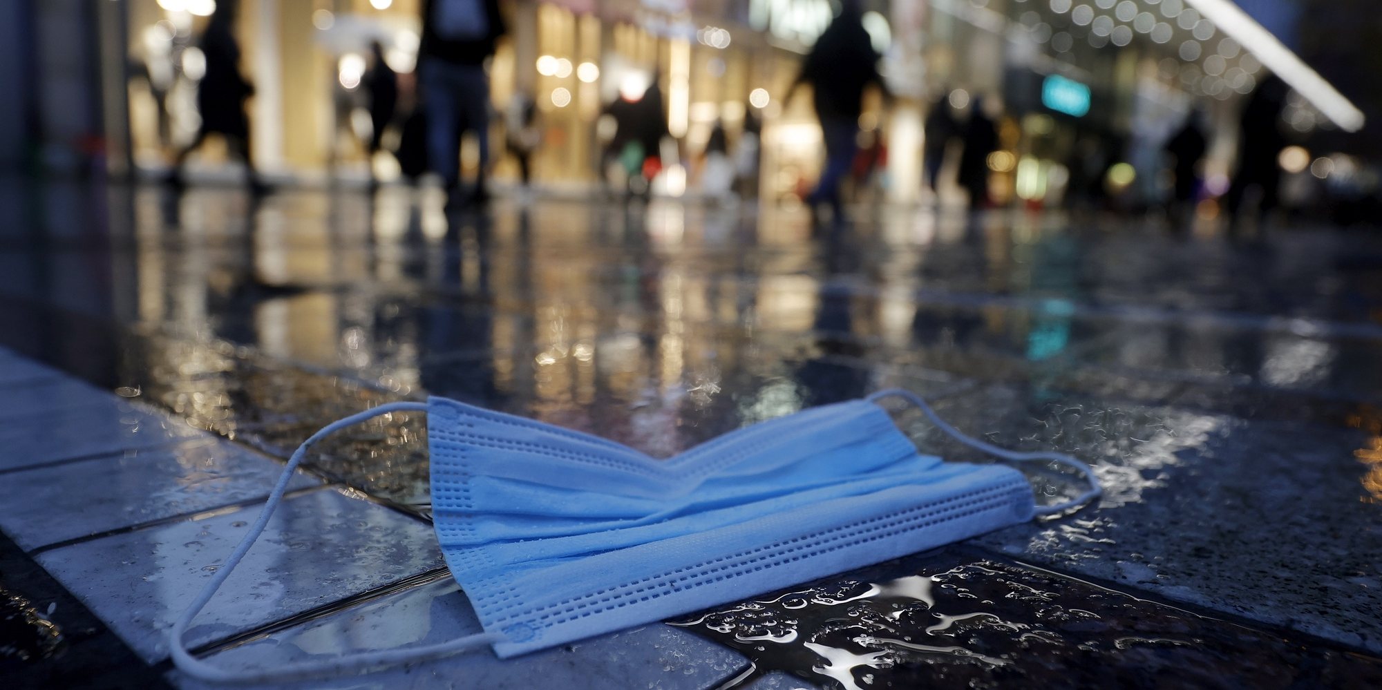 epaselect epa08885379 A protective face mask lies on the floor during shopping of the people in the city center at the &#039;Zeil&#039; in Frankfurt, Germany, 15 December, 2020. Due to an increasing number of cases of the COVID-19 pandemic caused by the SARS CoV-2 coronavirus, new nationwide restrictions have been announced to counteract a rise in infections, as the closing of the single store starting tomorrow 16 December.  EPA/RONALD WITTEK