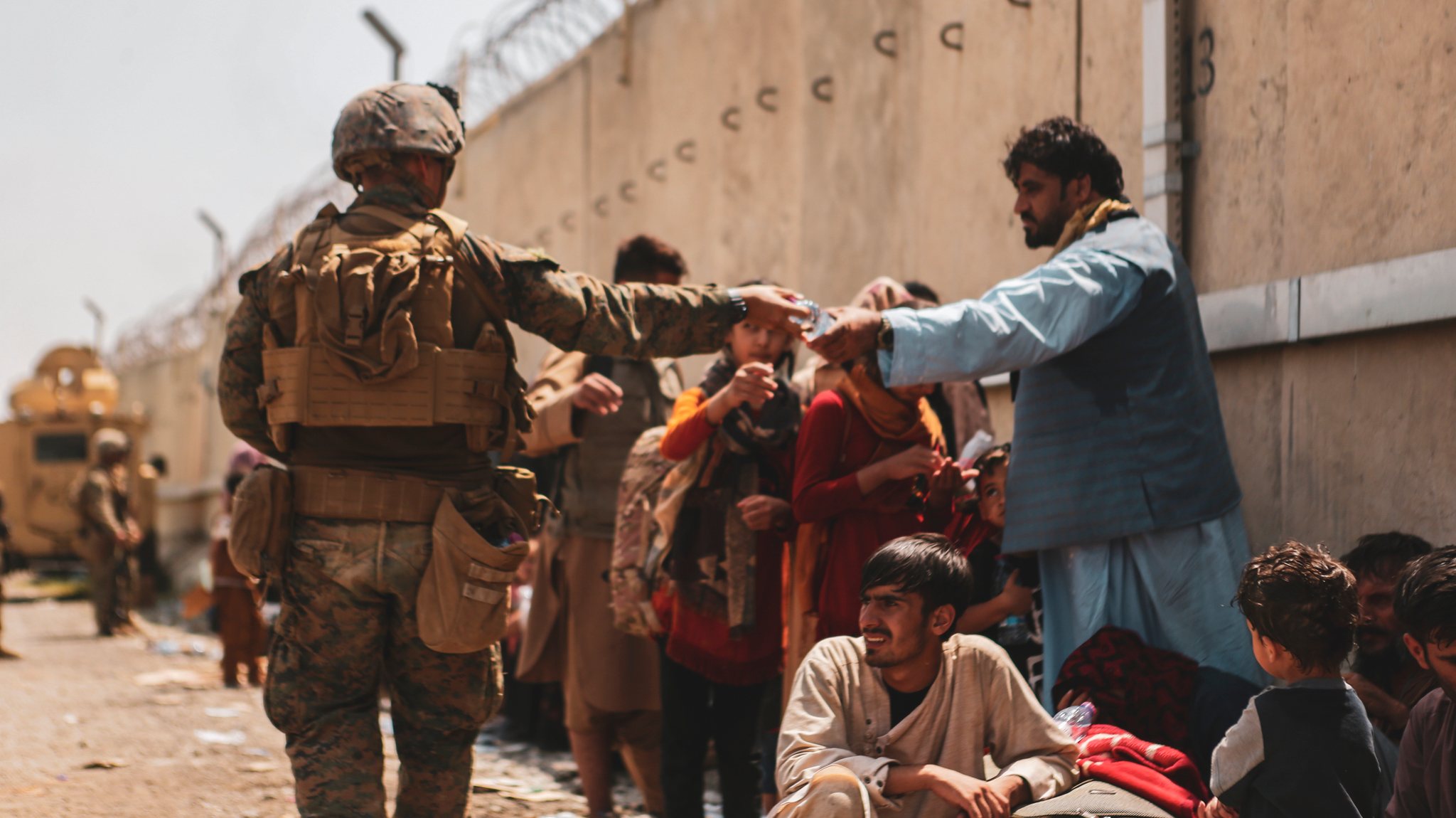Um militar norte-americano distribui água pelos afegãos que aguardam pela evacuação do aeroporto em Cabul