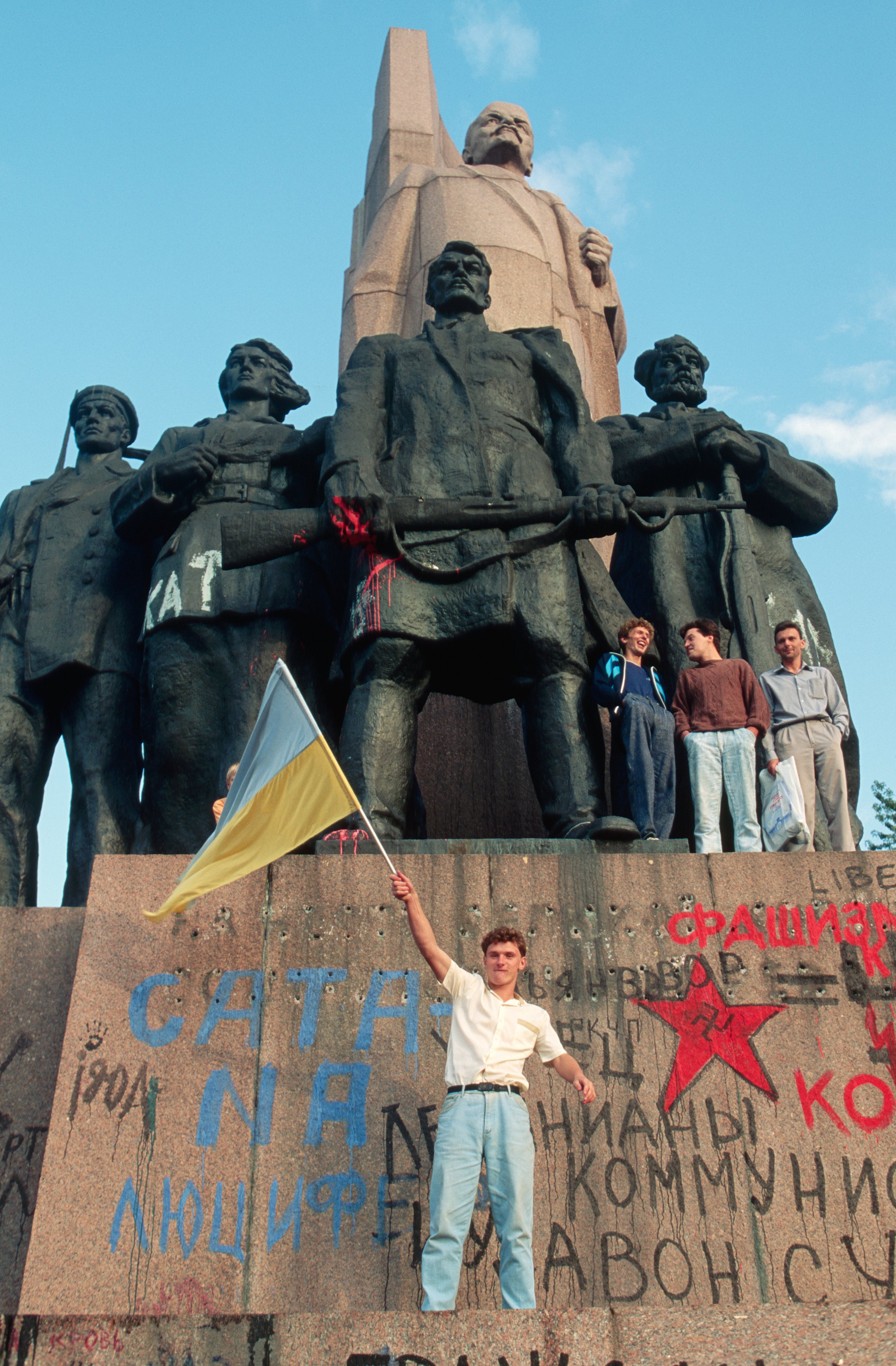 Young Man Waving Flag Under Ukraine Lenin Statue