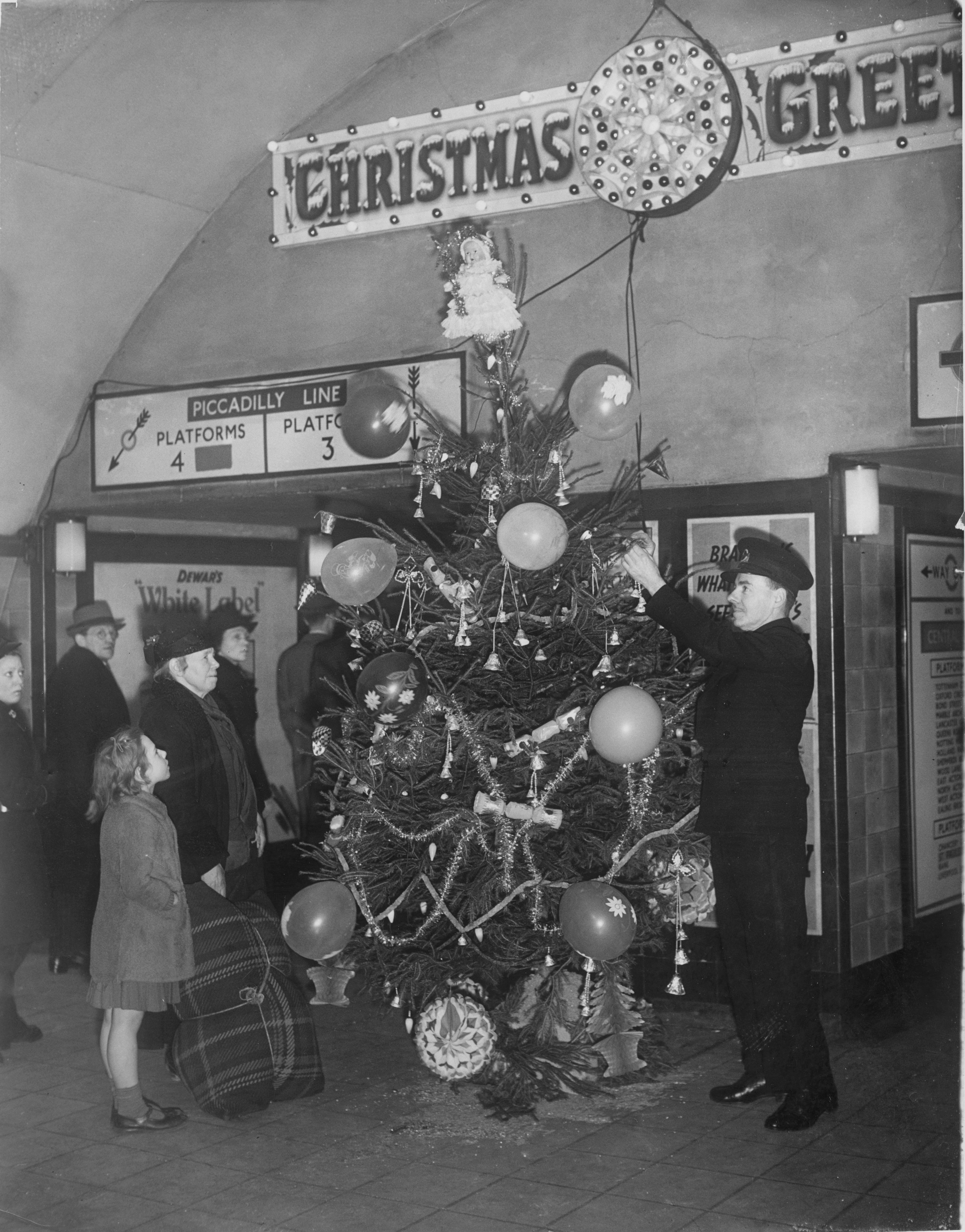 An underground railway guard decorating a Christmas tree at Holburn tube station during World War Two December 1940