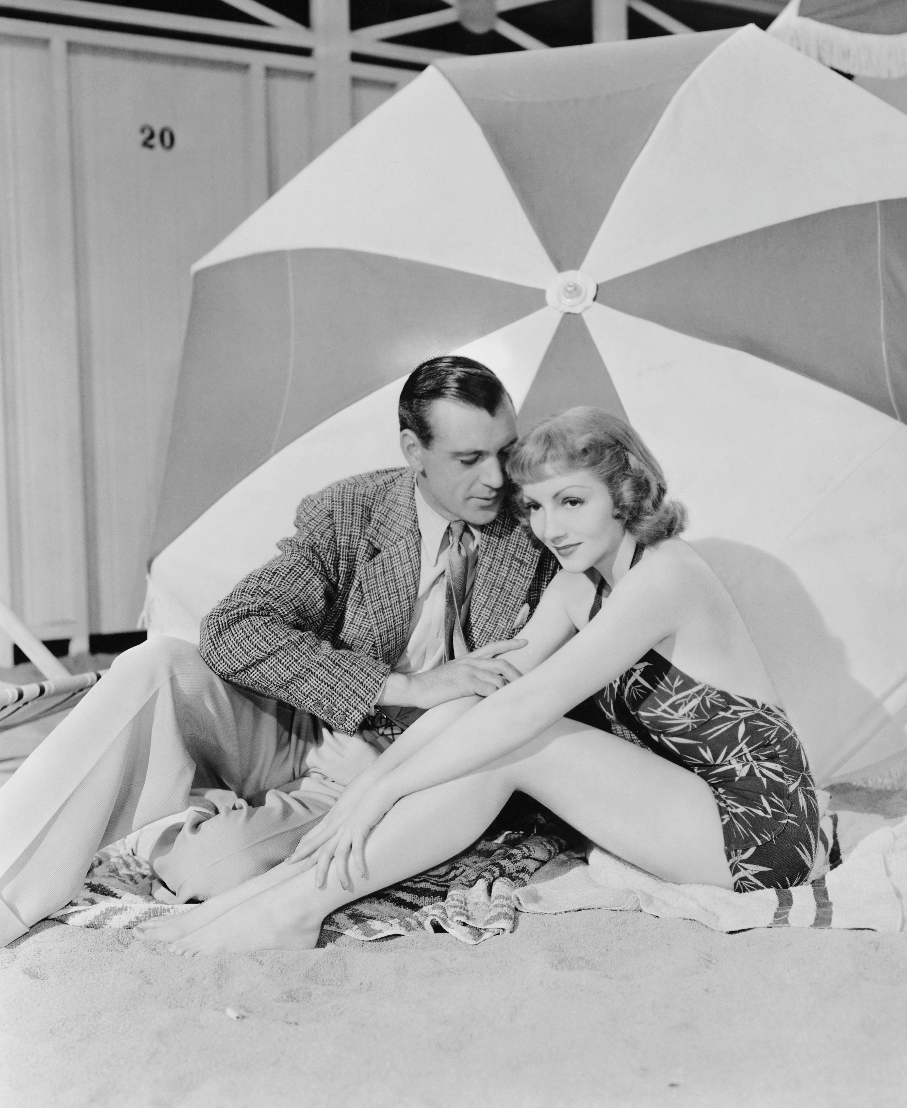 Gary Cooper and Claudette Colbert Seated Under Umbrella