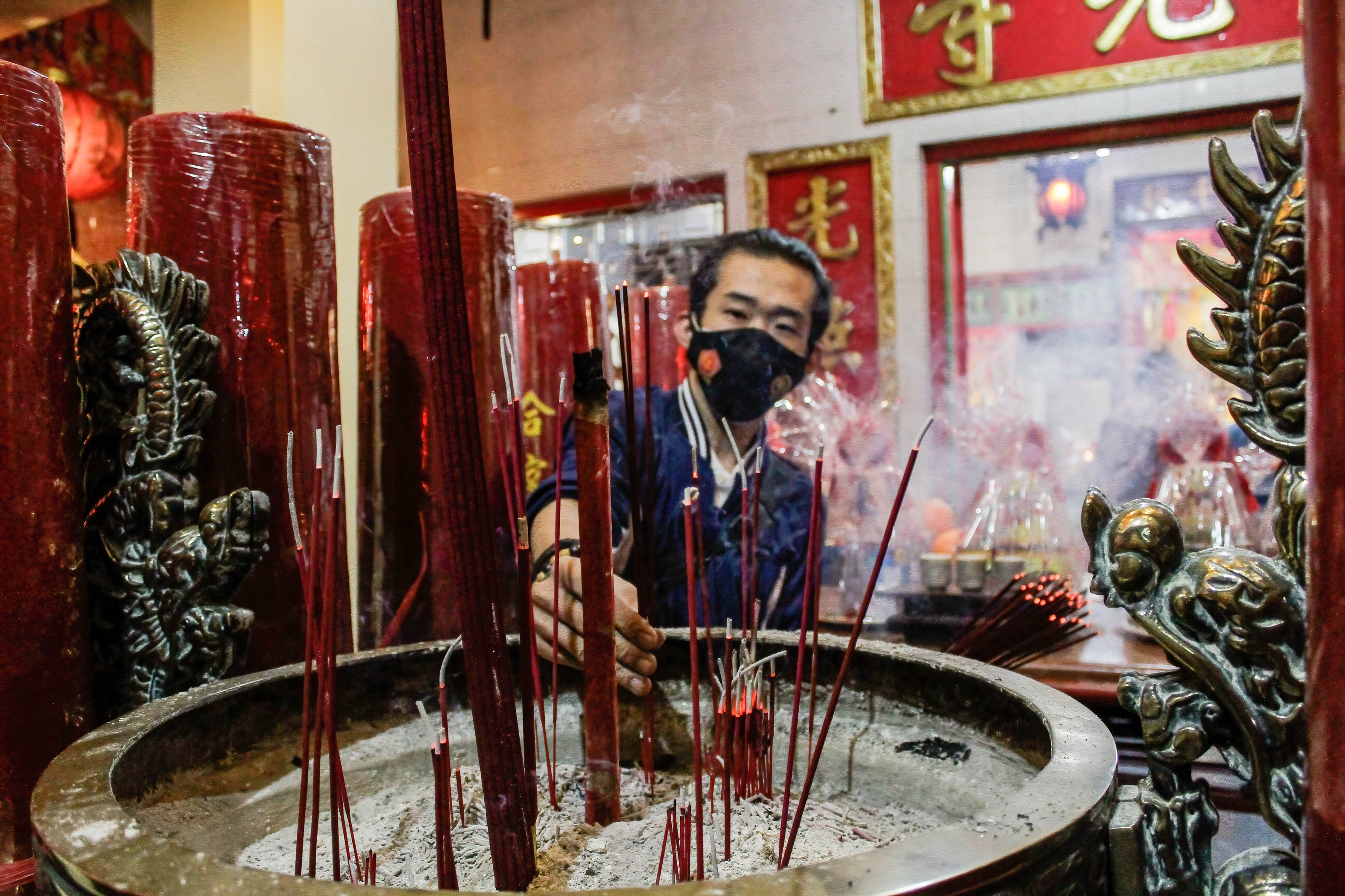 A Chinese man prays with incense sticks during the