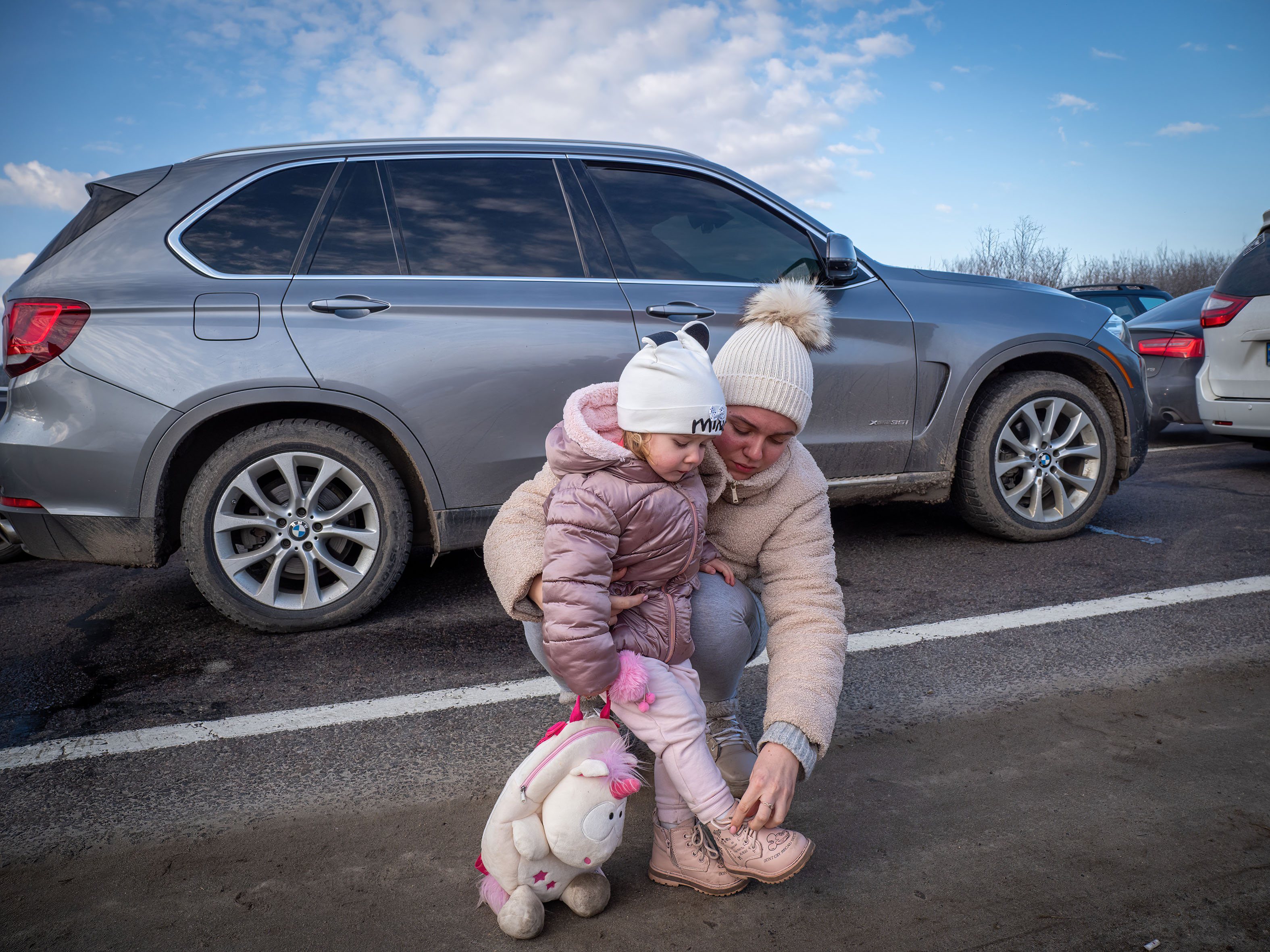 Uma mulher a filha esperam fora do carro para atravessar a fronteira polaca
