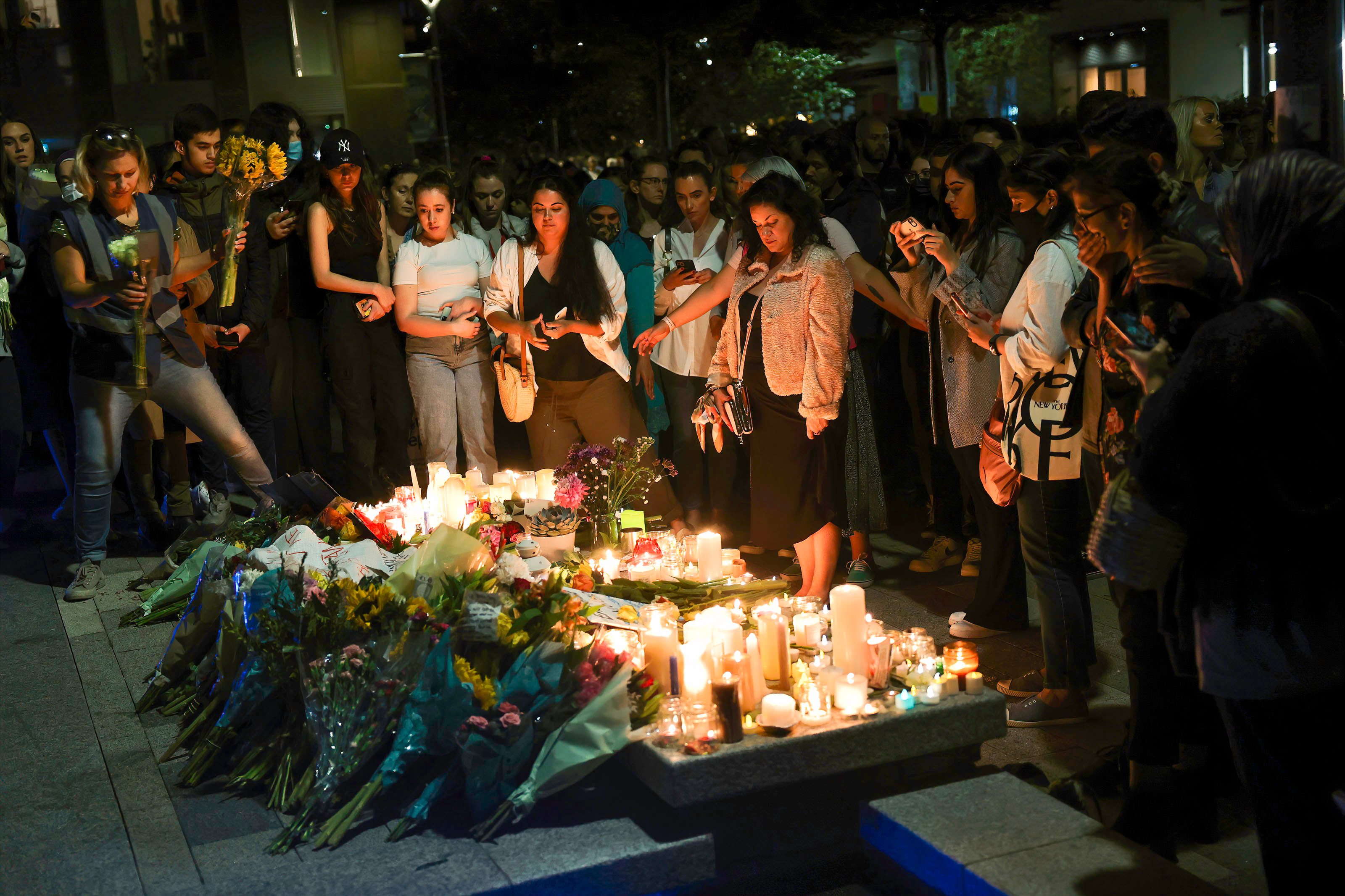 Participants are seen placing lit candles and flowers during