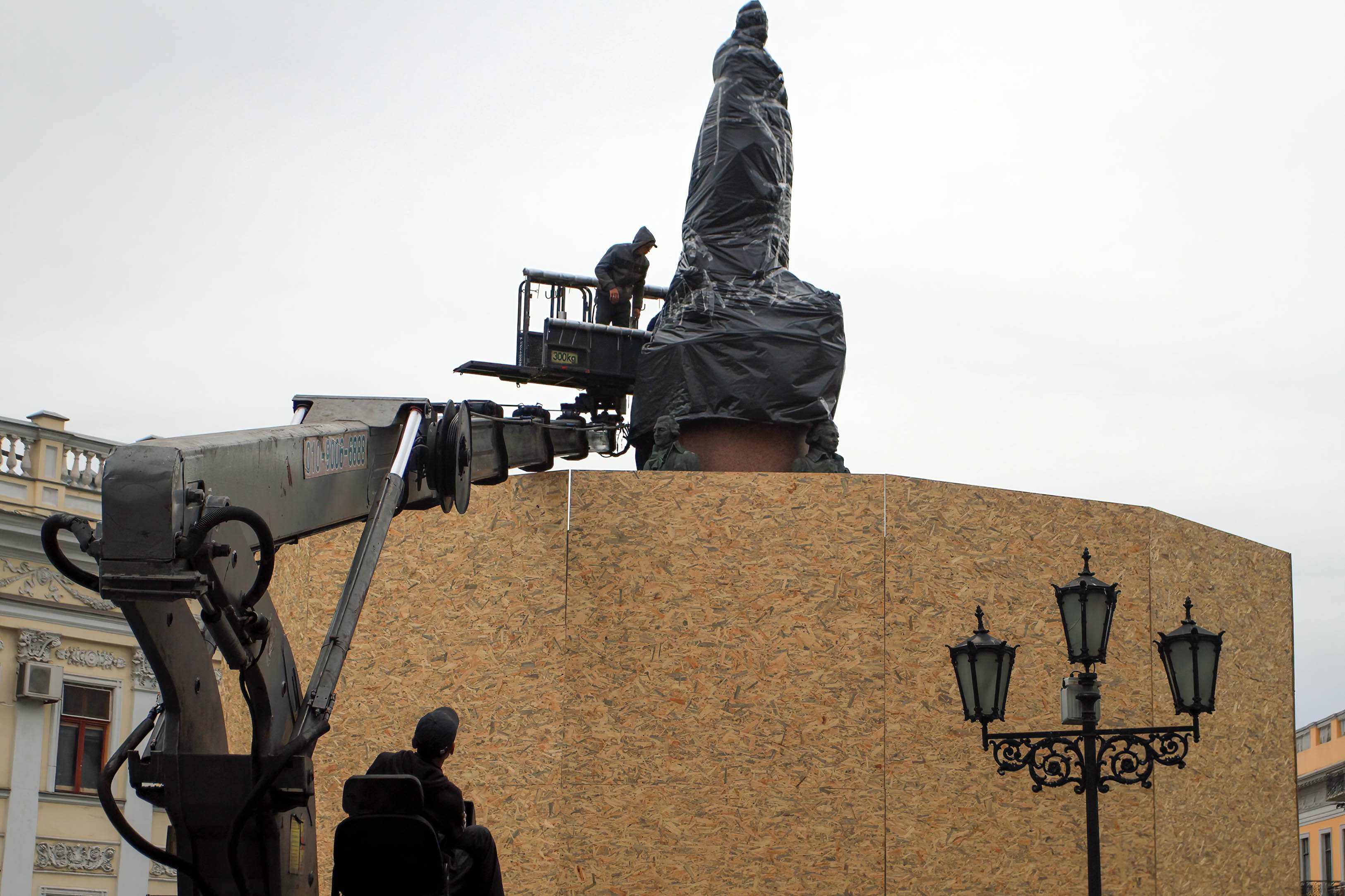 Workers are seen wrapping a monument to Catherine II with