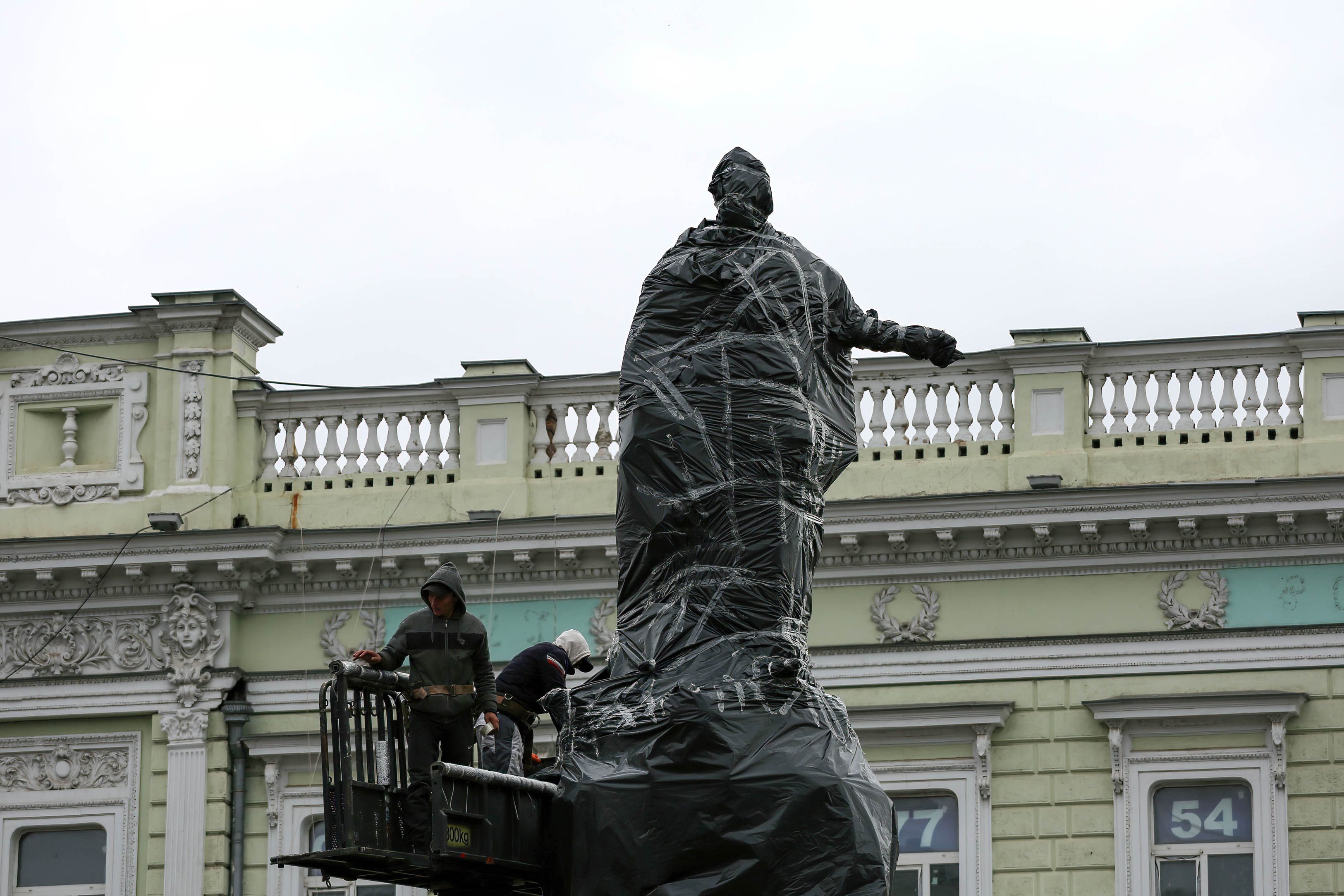 Workers are seen wrapping a monument to Catherine II with a