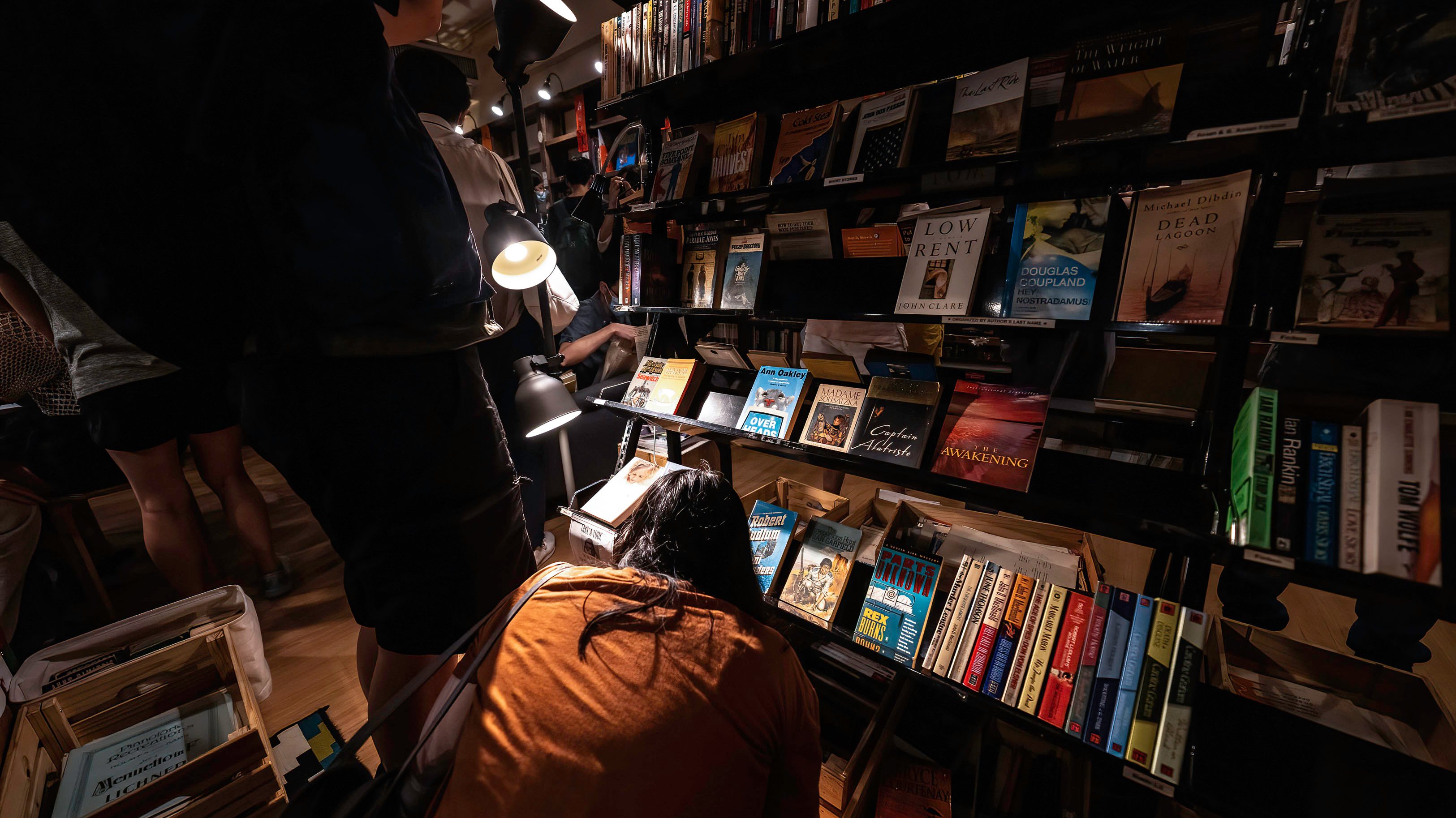A woman browses the books on a bottom shelf.Crowds of