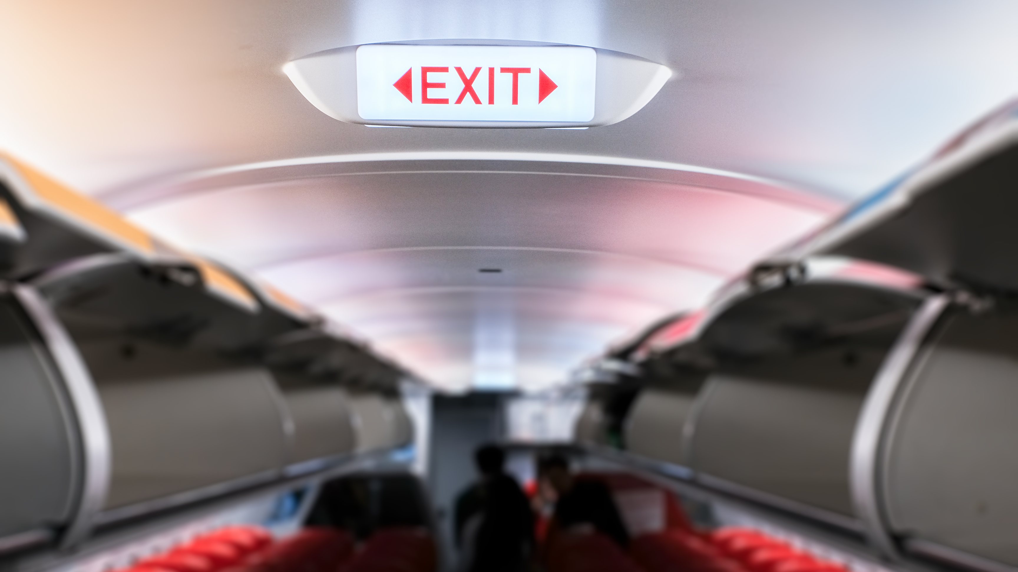 Emergency exit sign on ceiling inside passenger aircraft cabin