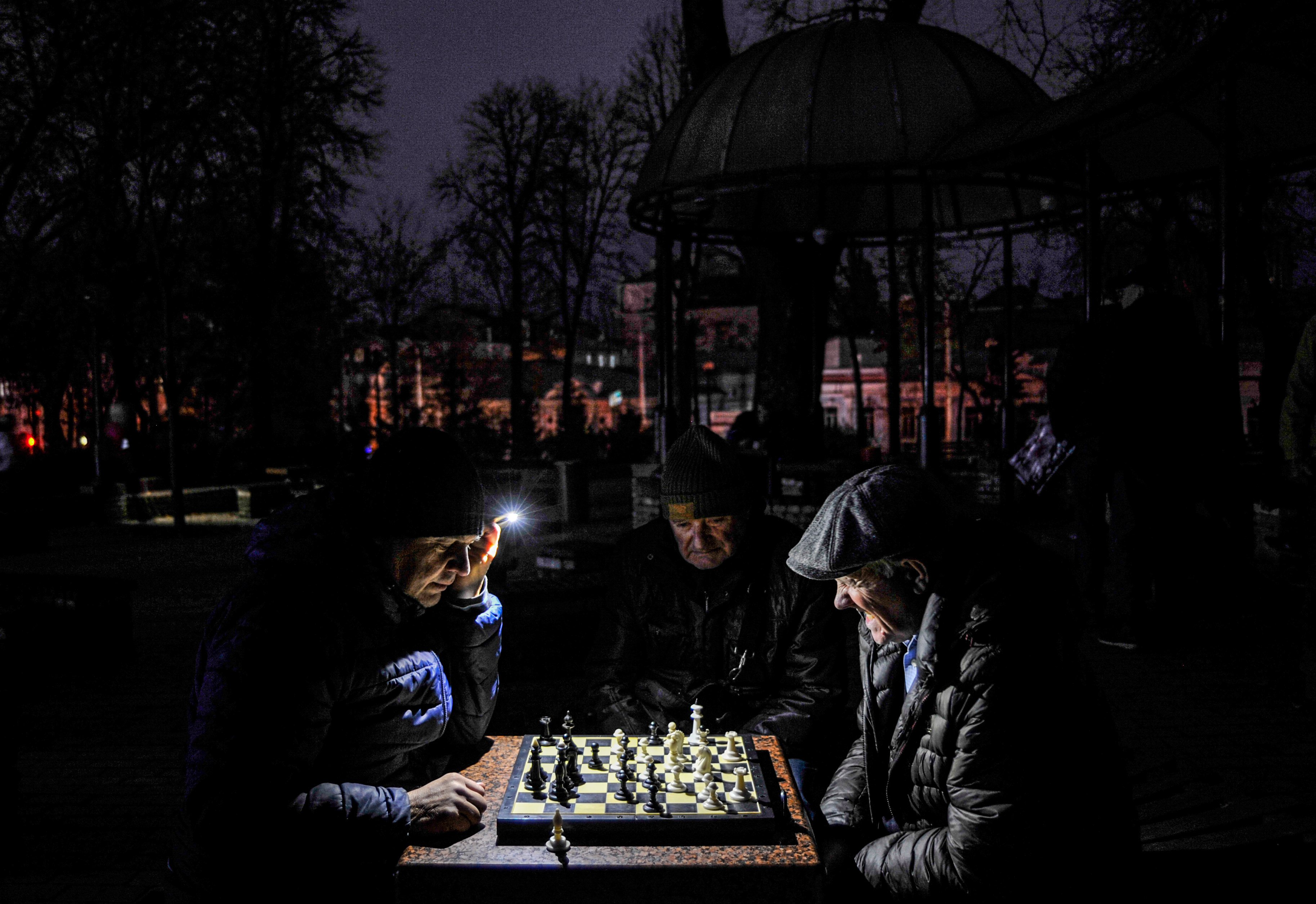 Men seen playing chess by a flashlight in a park in Kyiv