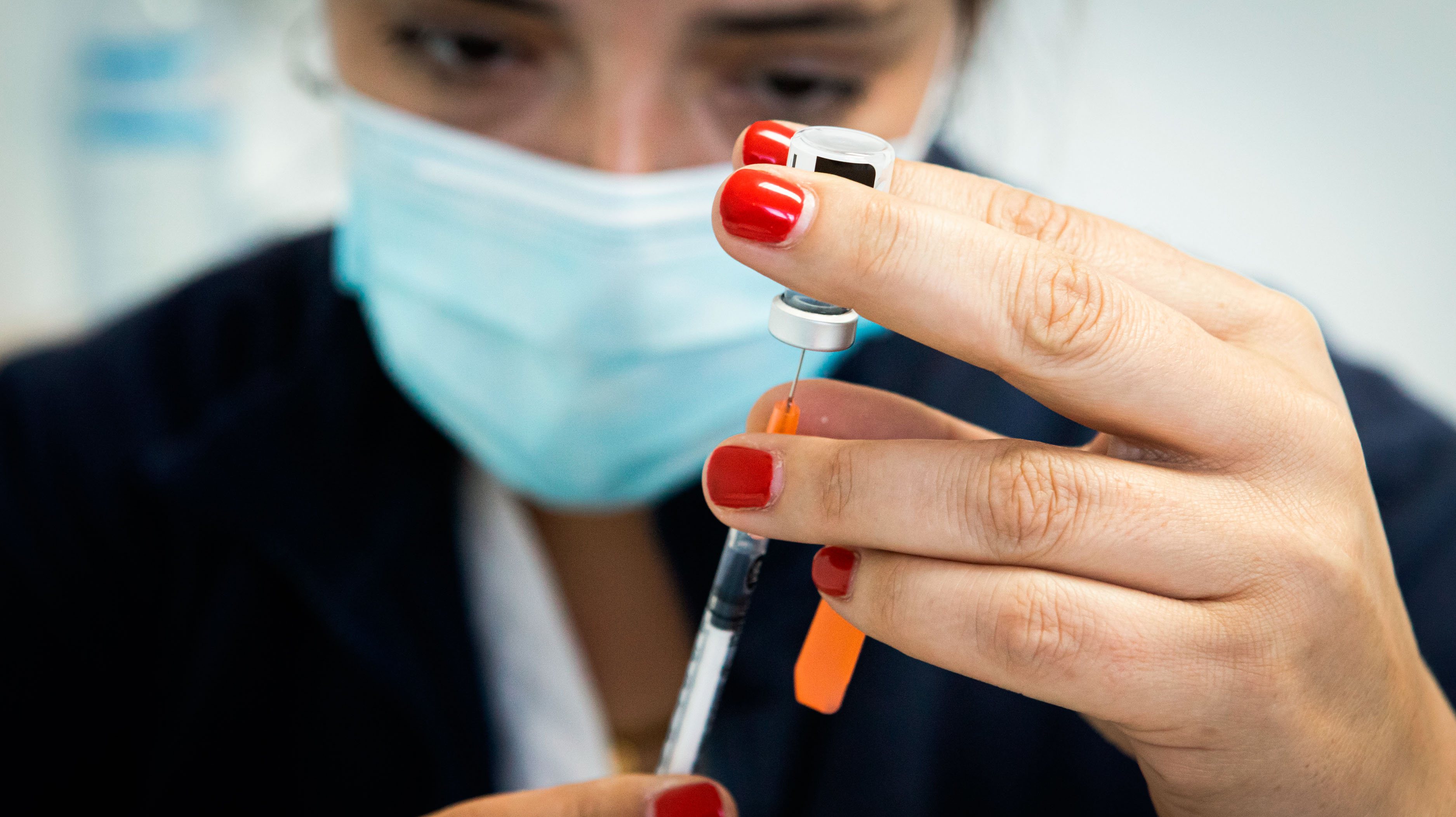 A nurse fills a syringe with the Cominarty vaccine.The