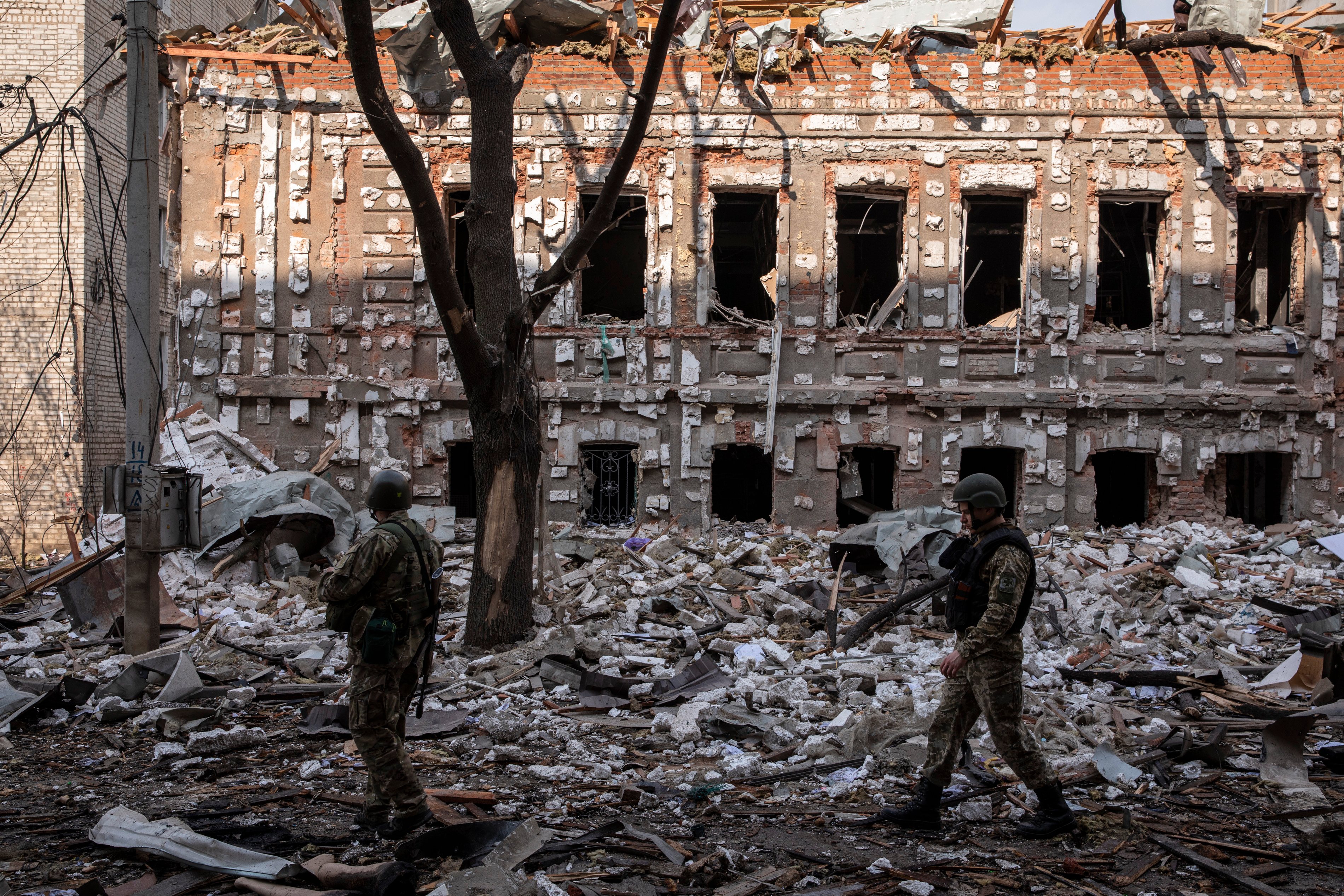 Two Ukrainian military soldiers walk on the debris caused by