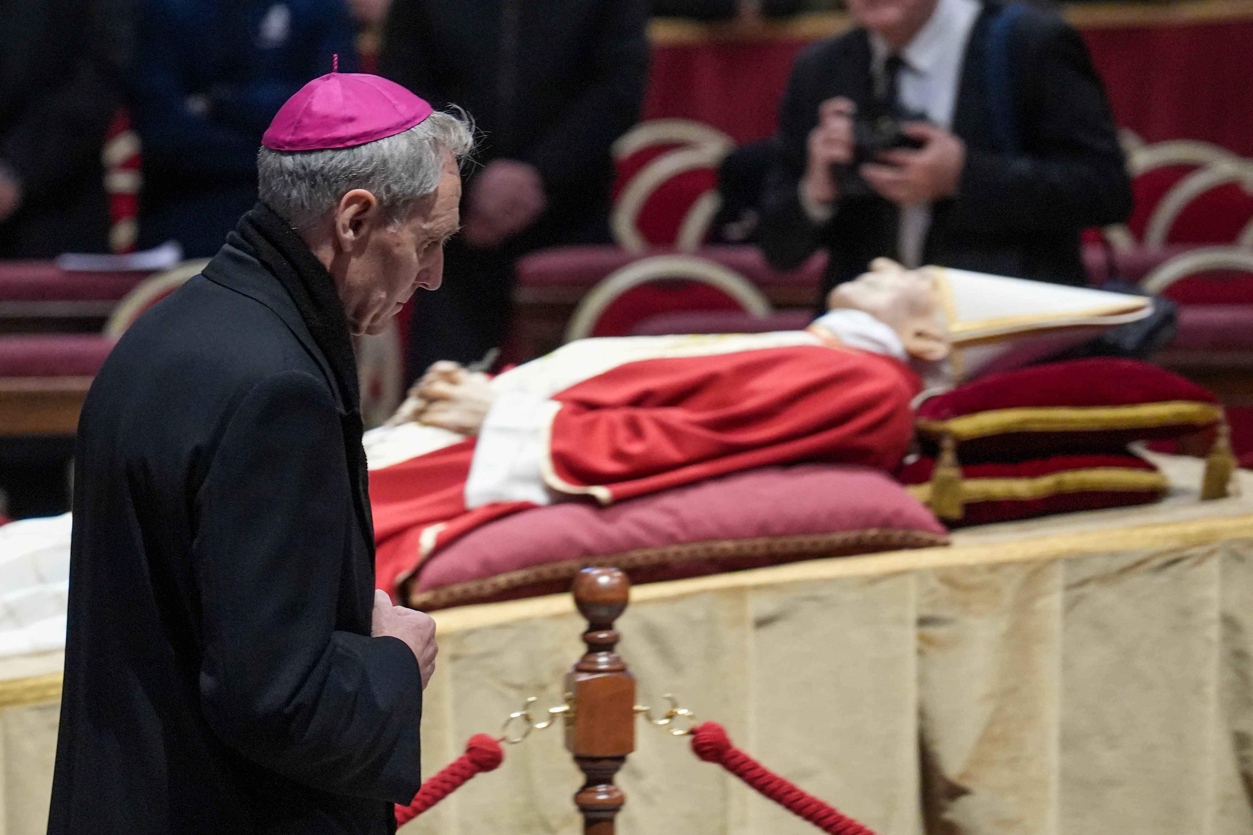 Archbishop Georg Gänswein prays in front of the body of