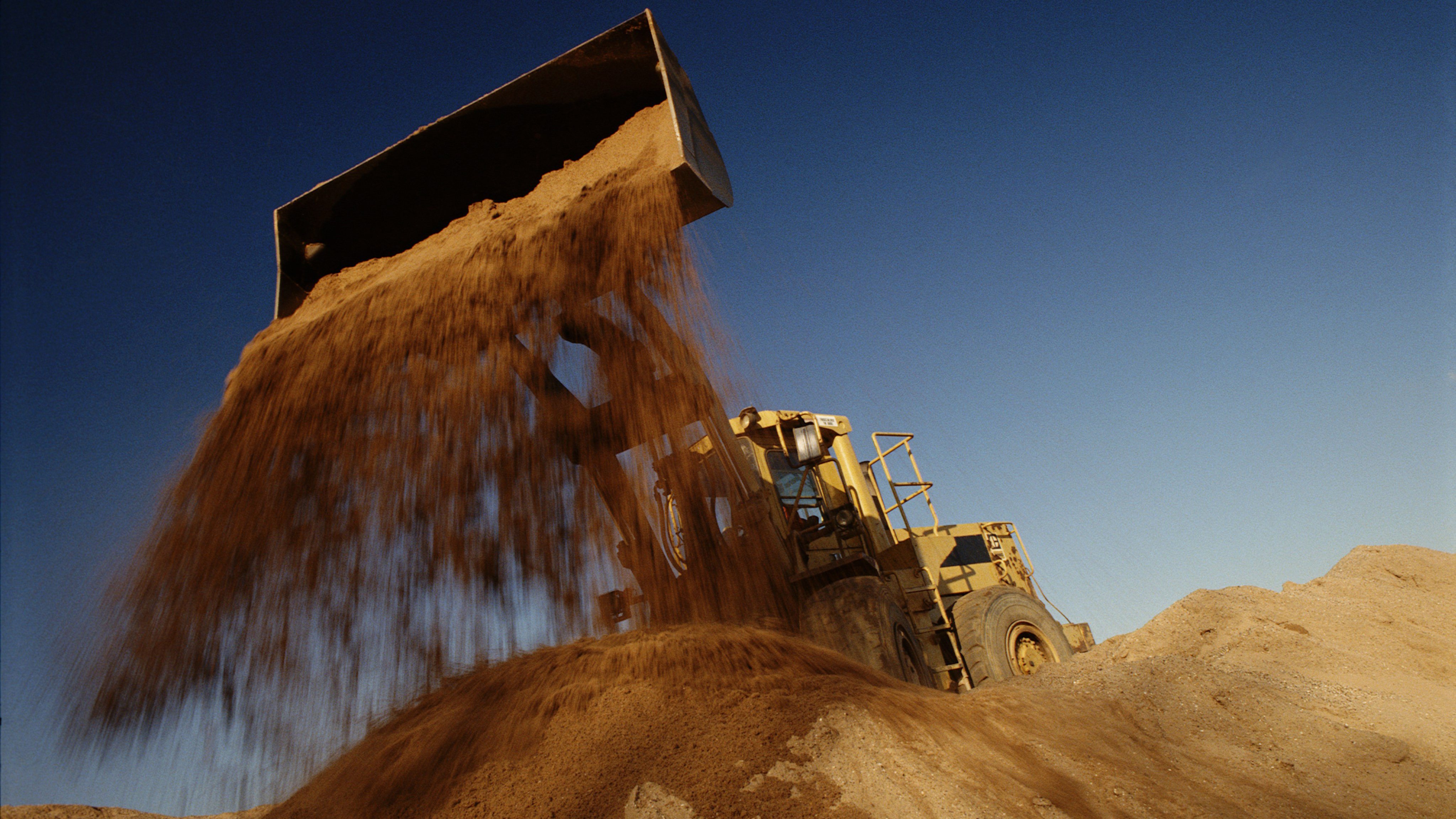Earth mover in quarry dumping sand, low angle view