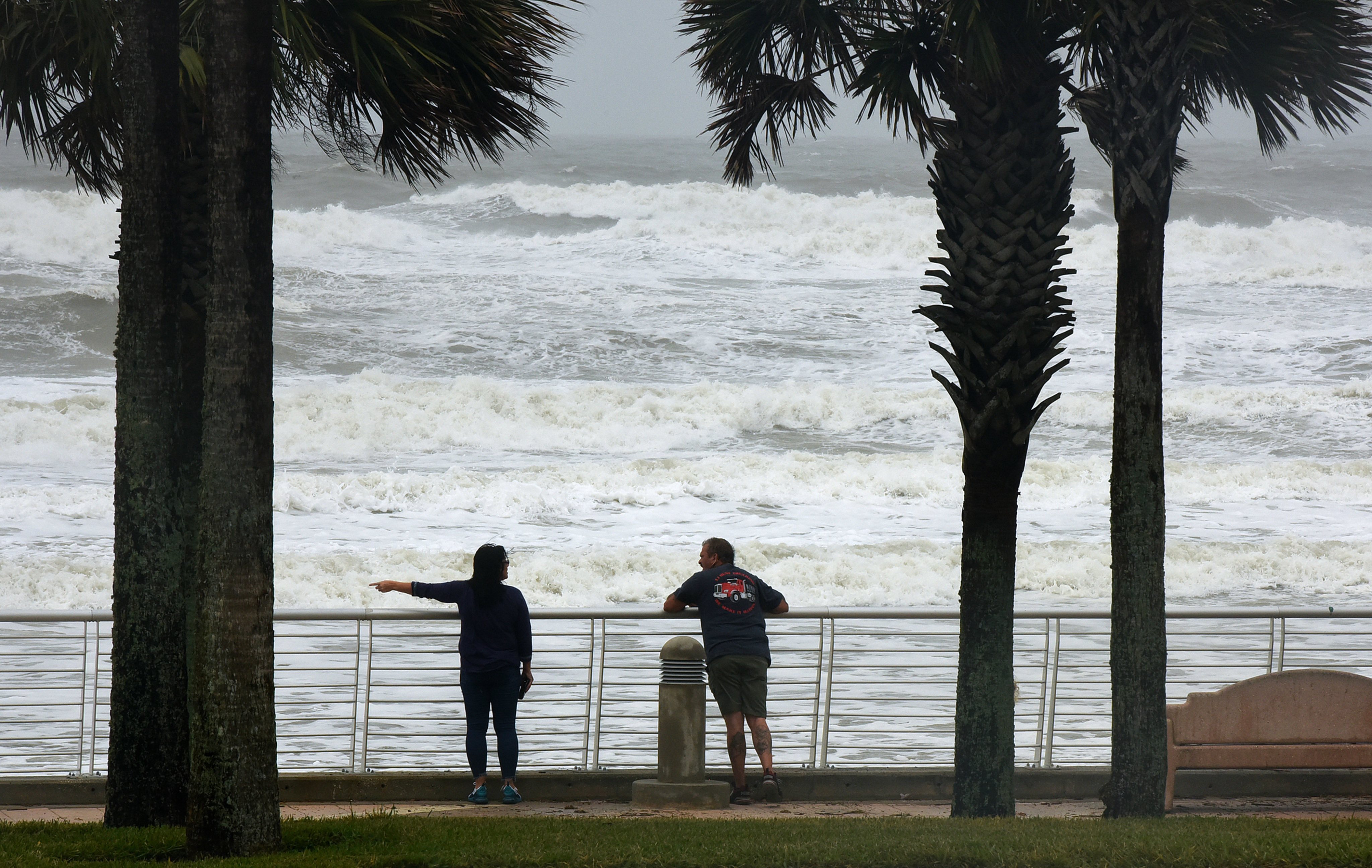 A couple watches as waves crash near the pier at Daytona