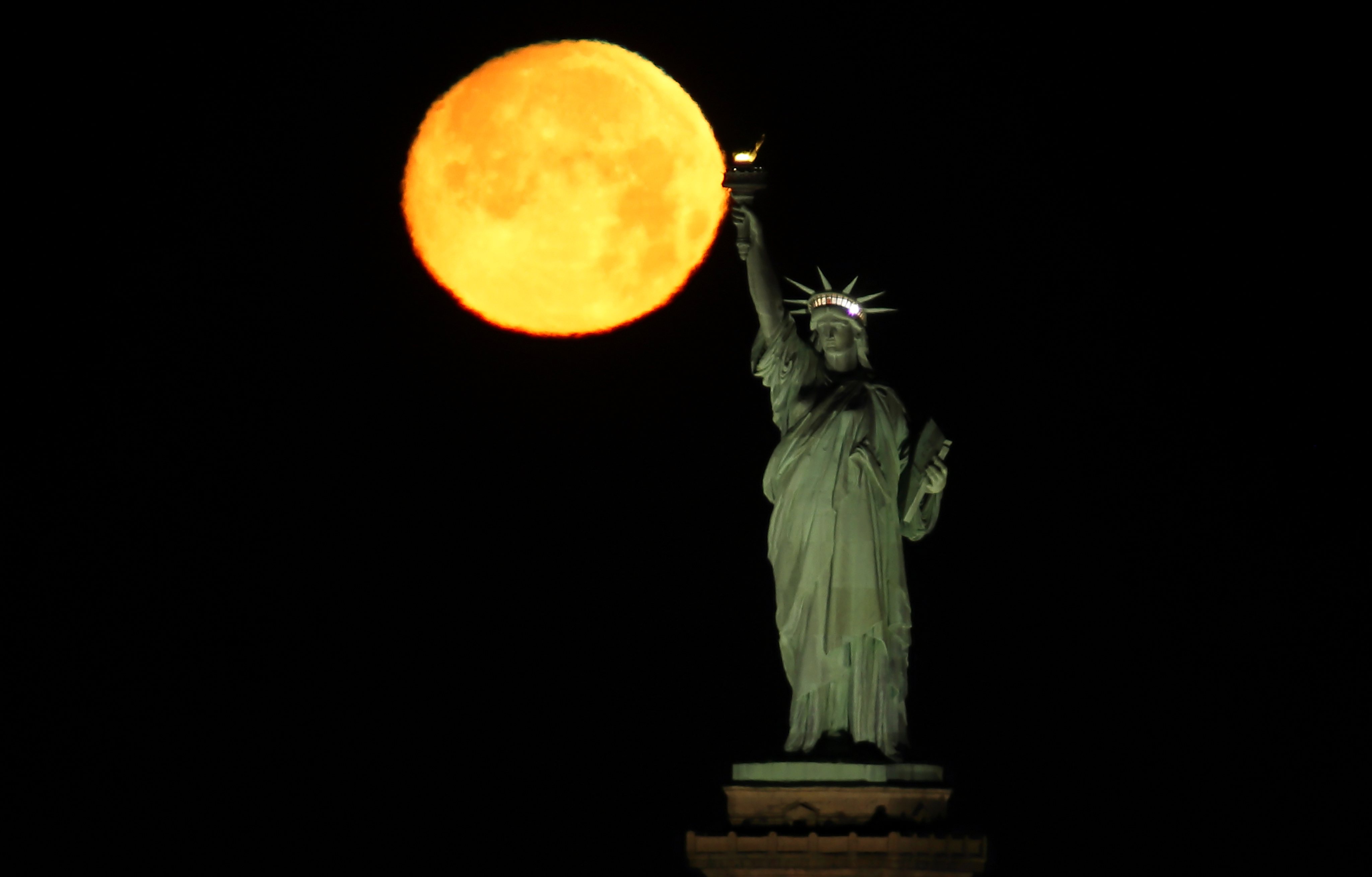 Wolf Moon Sets Behind the Statue of Liberty in New York City