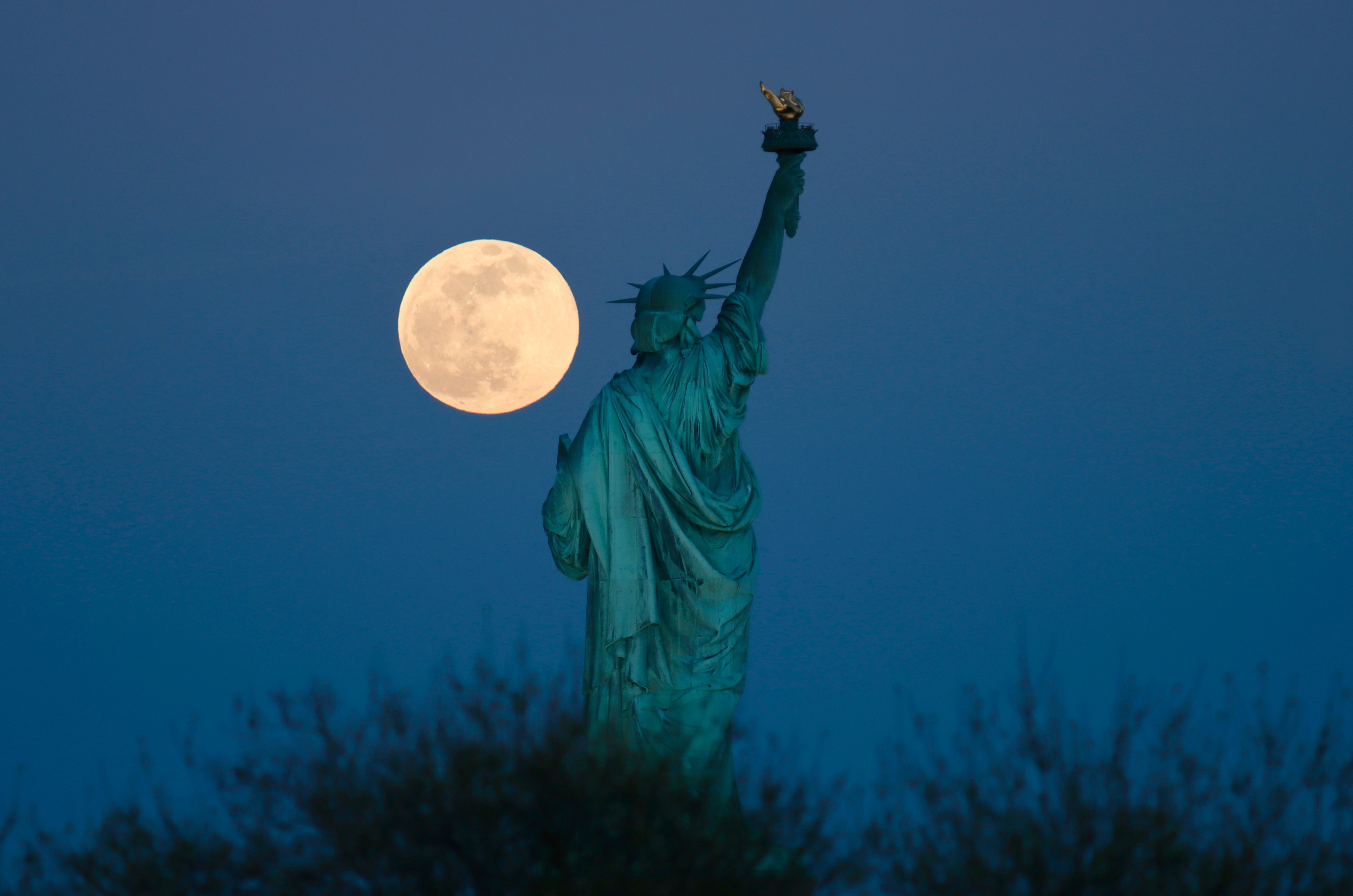 Super Pink Moon Rises Next to the Statue of Liberty in New York City