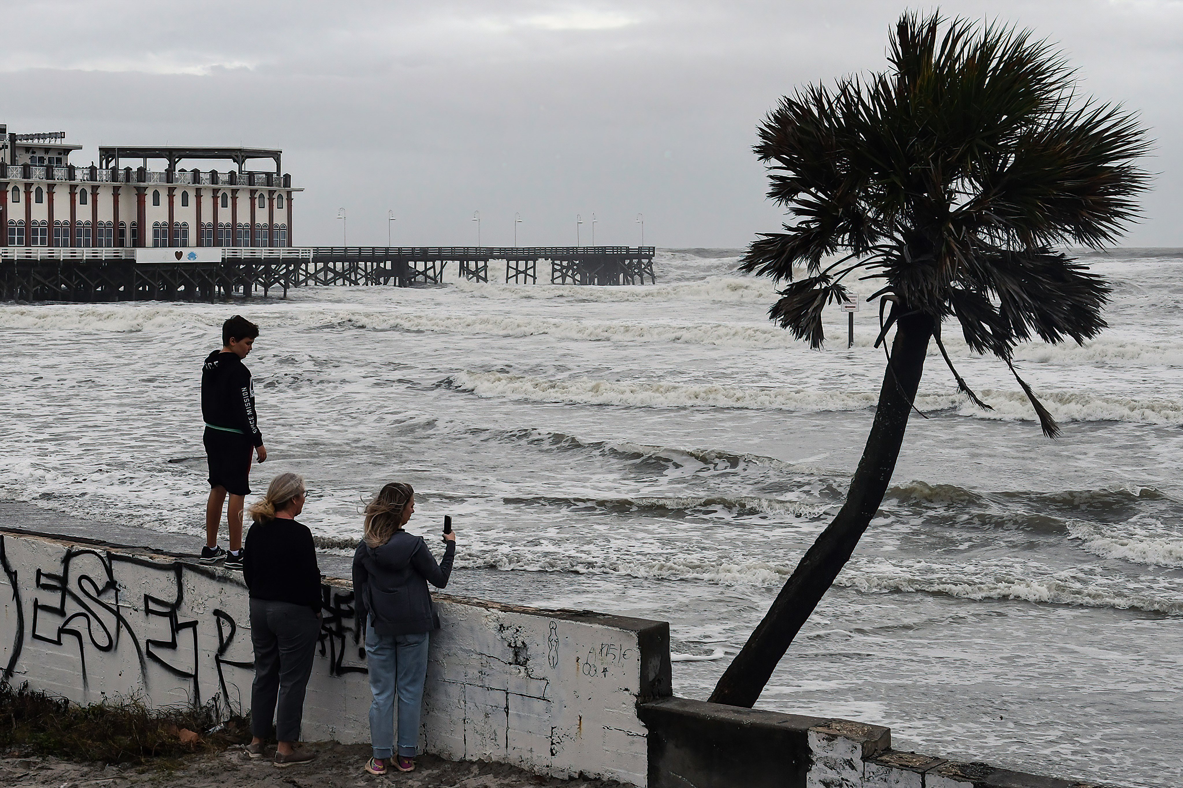 People watch the rough surf near the pier at Daytona Beach