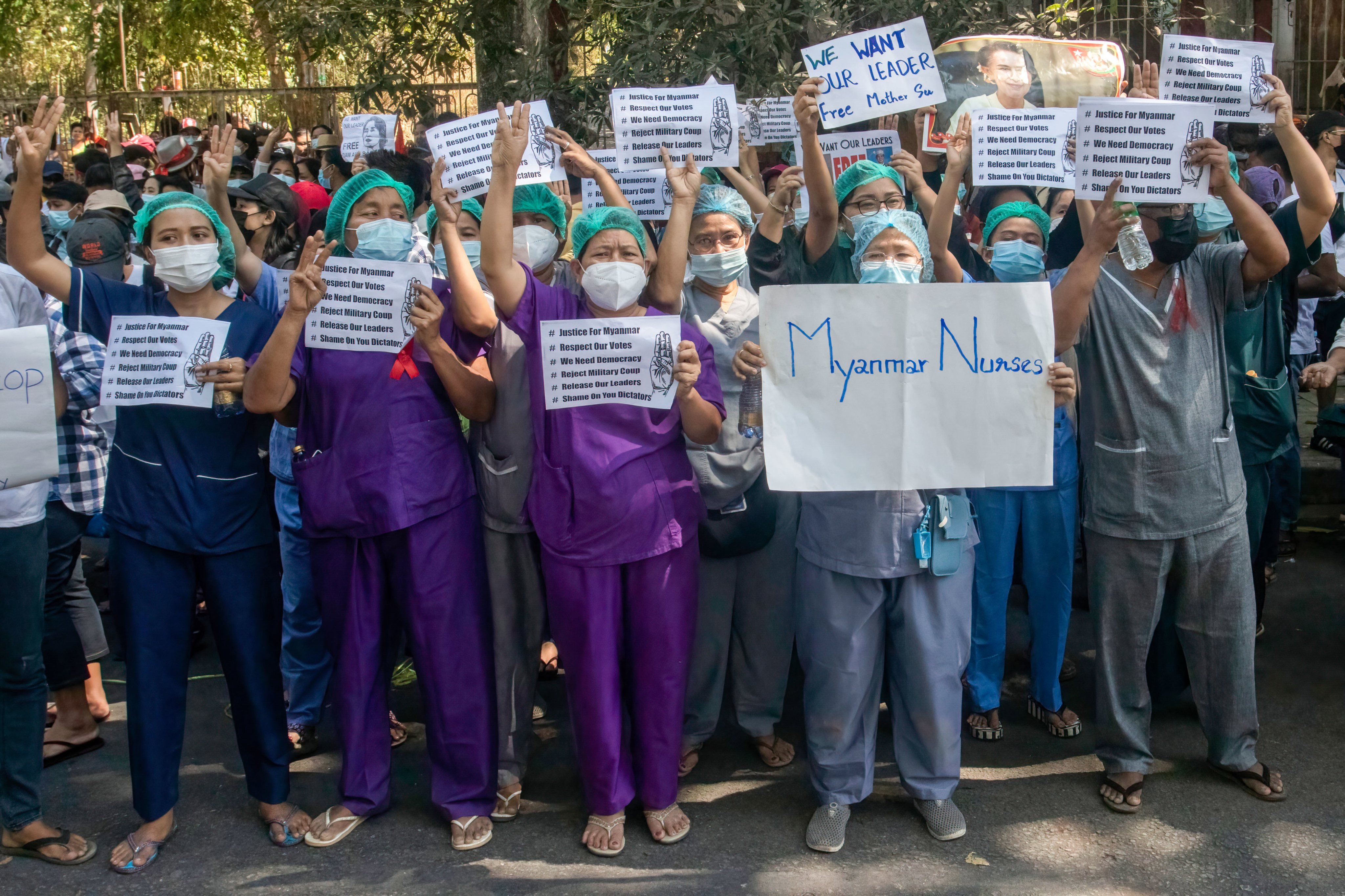 Nurse protesters display signs and raise three finger
