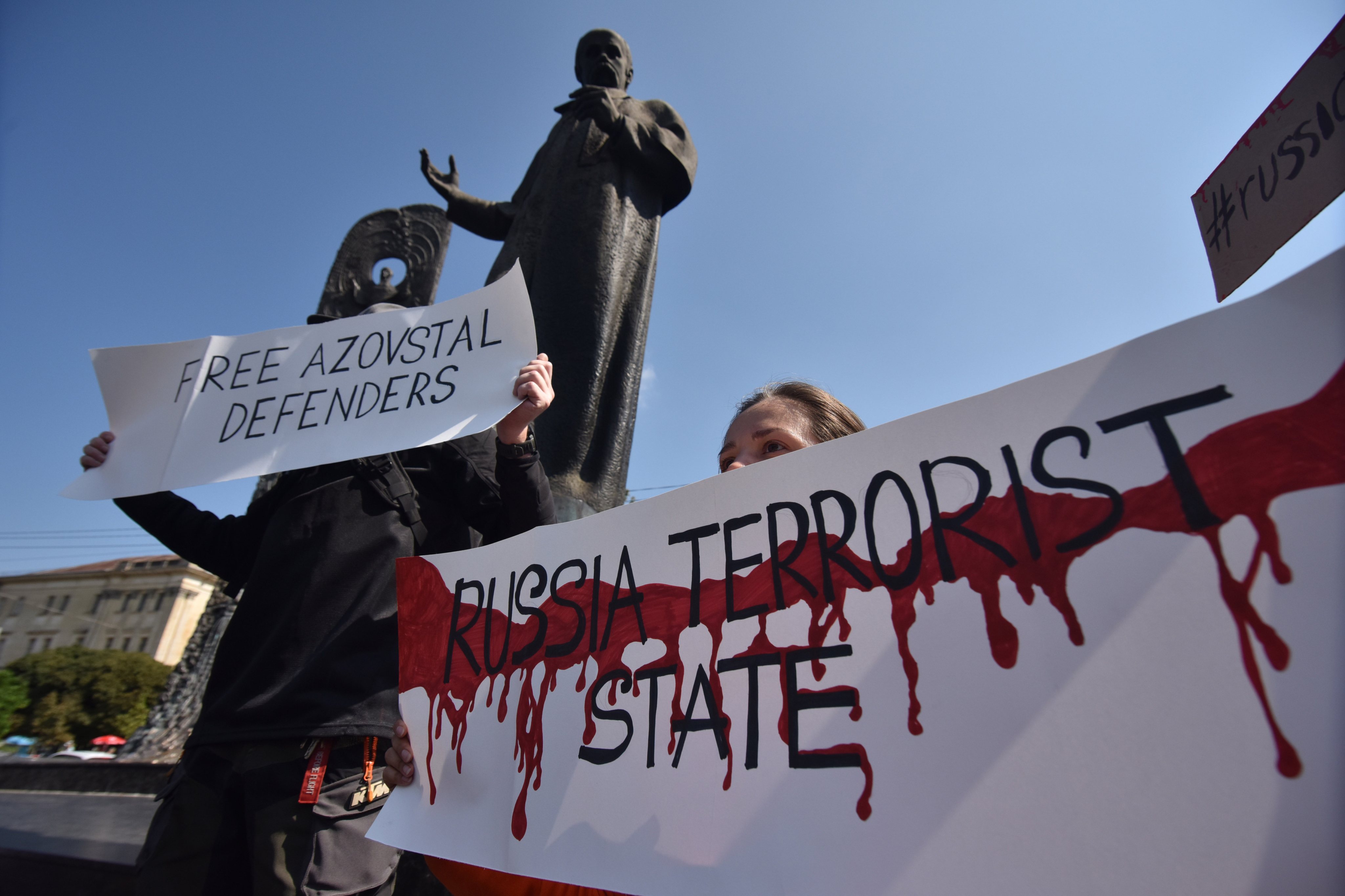 A protester holds a placard calling Russia a terrorist State