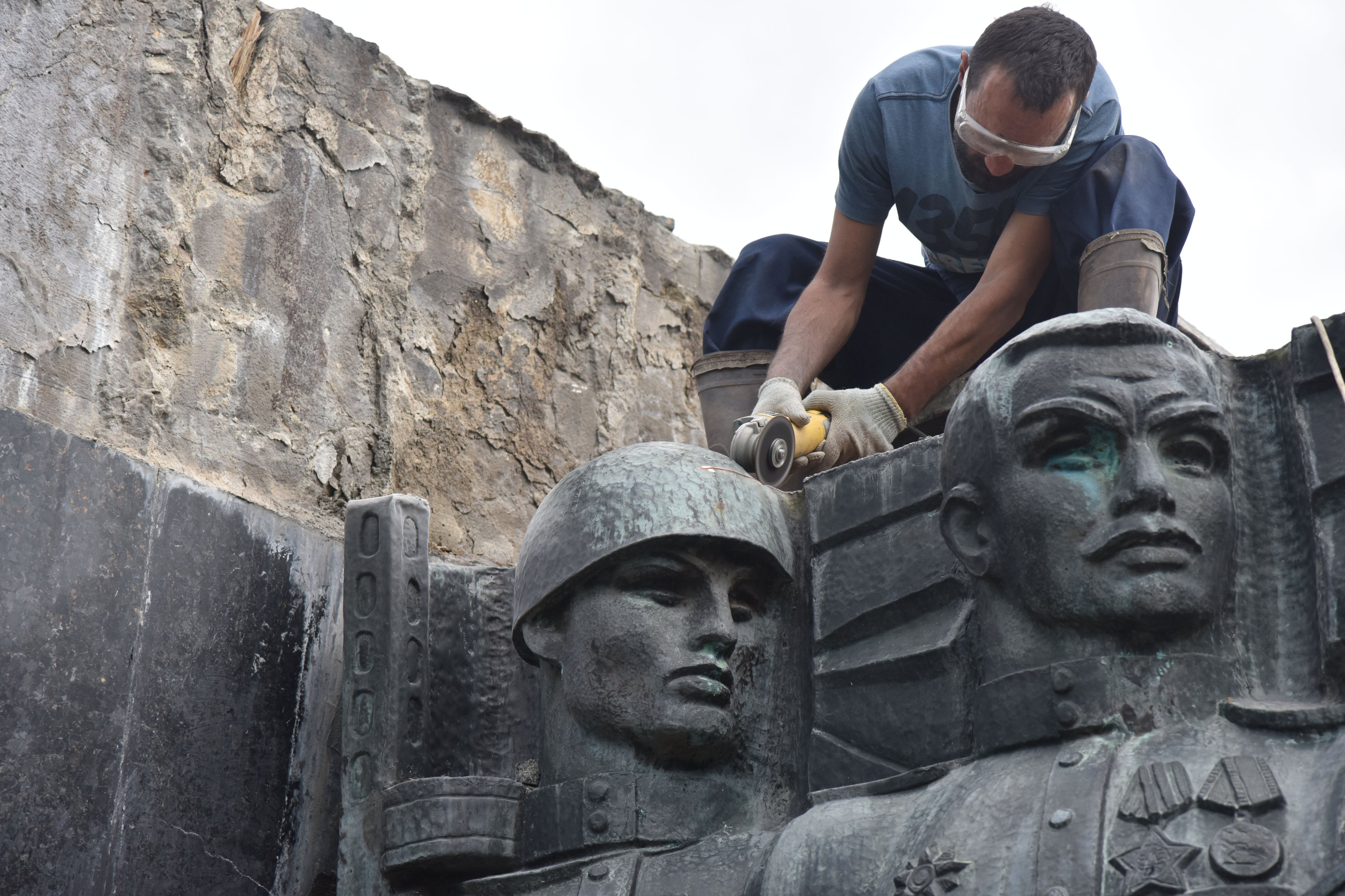 A worker saws part of the bas-relief on the Monument of