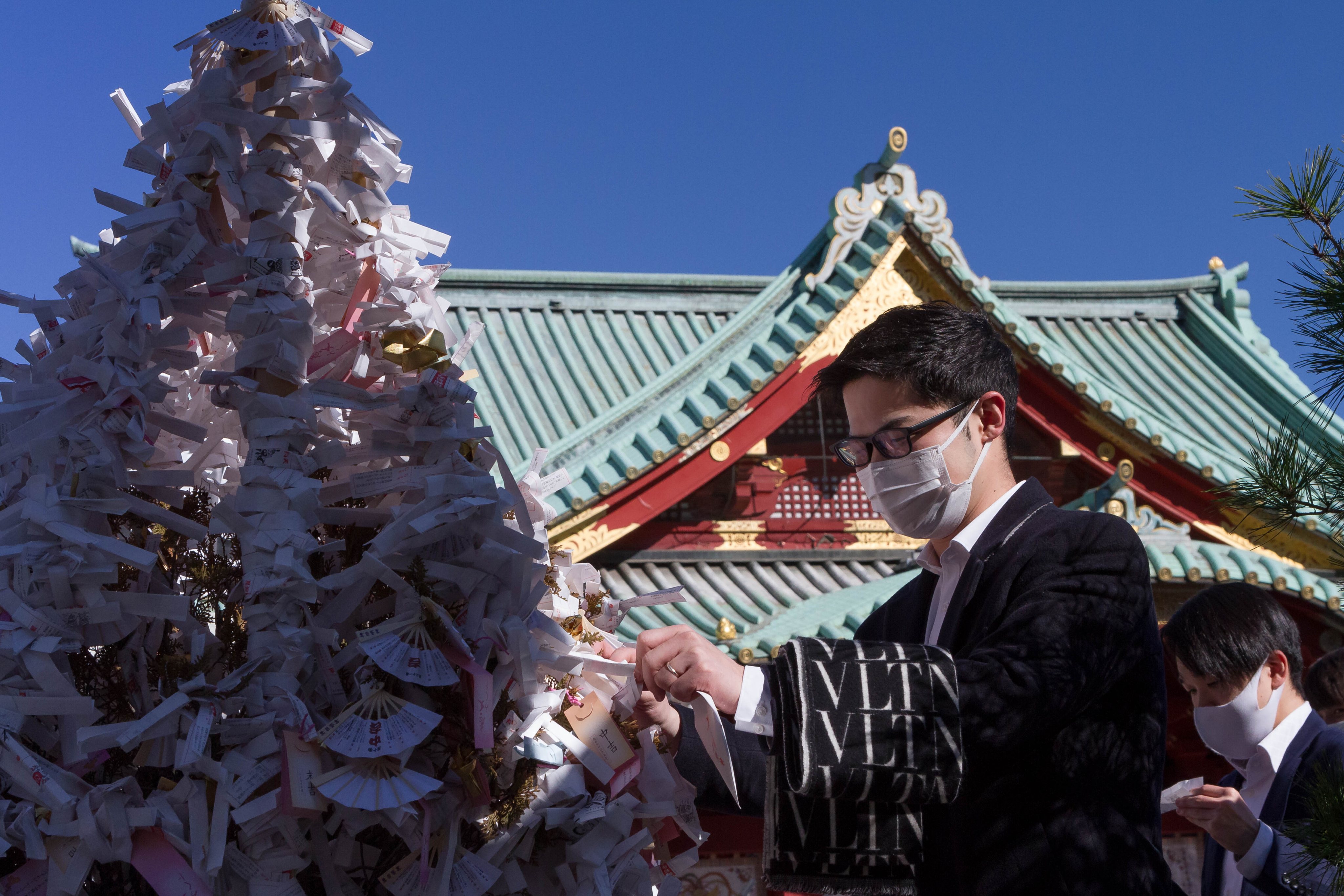 A man leaves a fortune paper, called omikuji, as  people