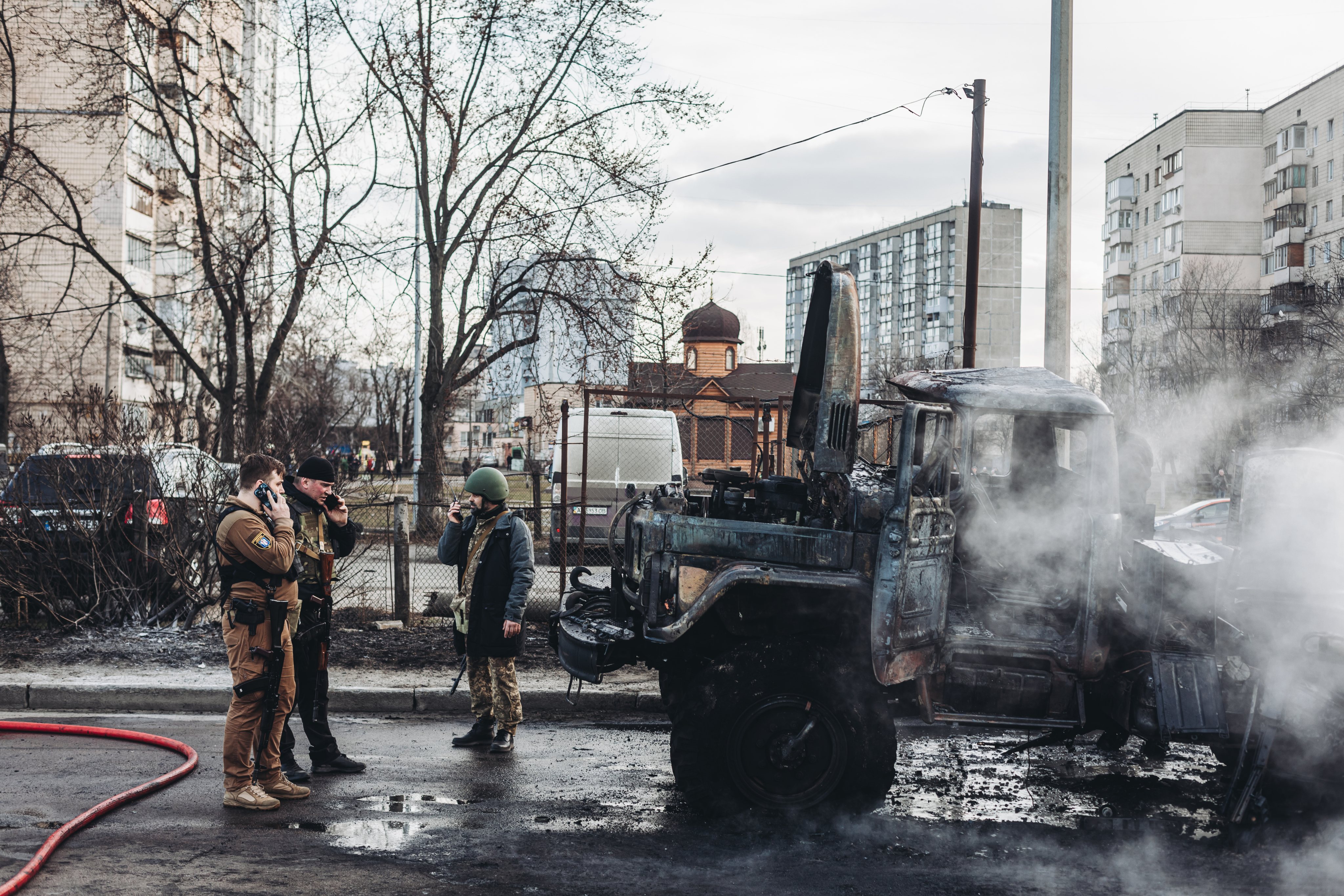 Soldados ucranianos olham para o seu veículo militar incendidado