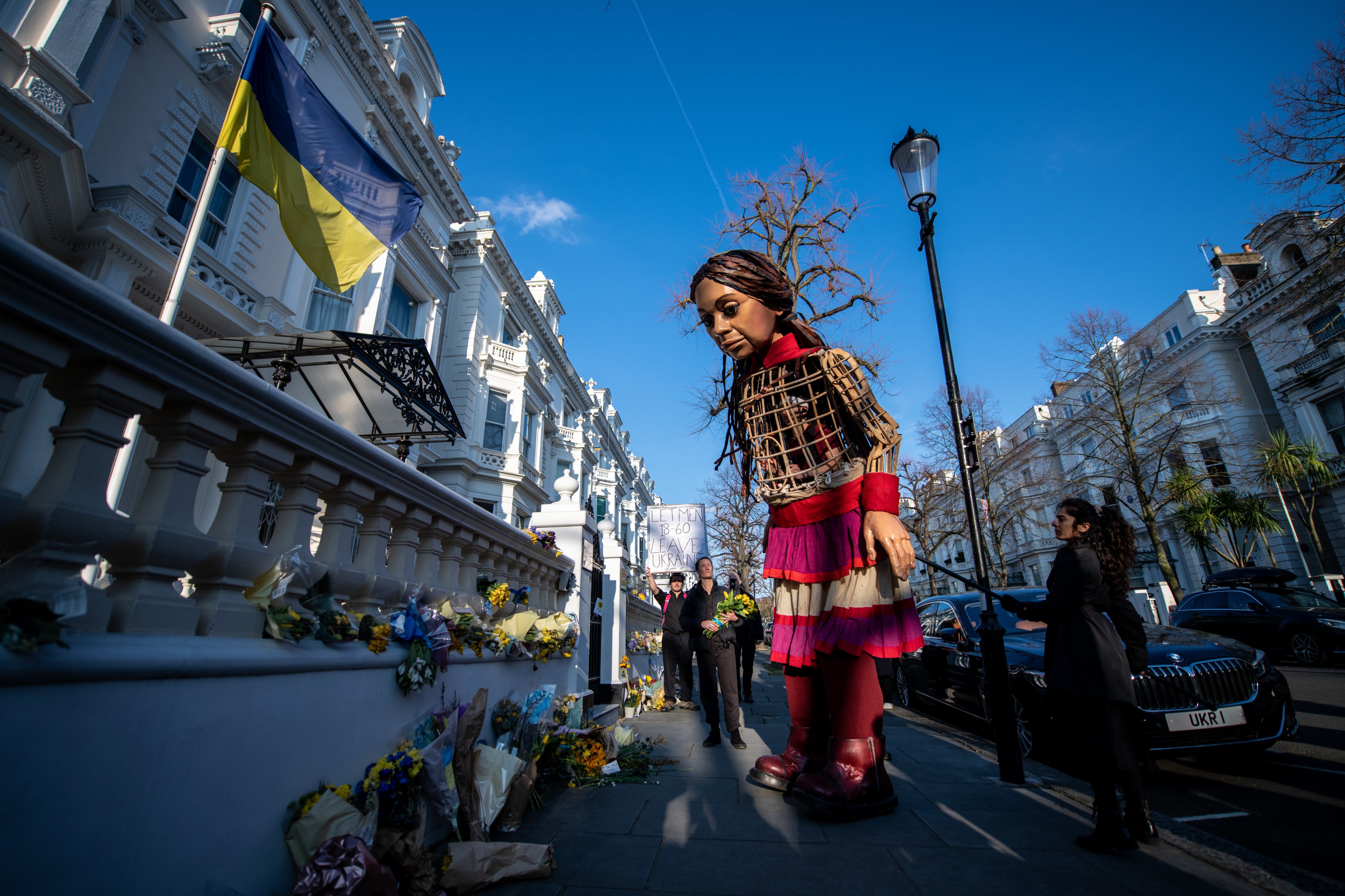 A &quot;Pequena Amal&quot;, fantoche que representa uma criança síria refugiada, coloca flores na embaixada da Ucrânia em Londres