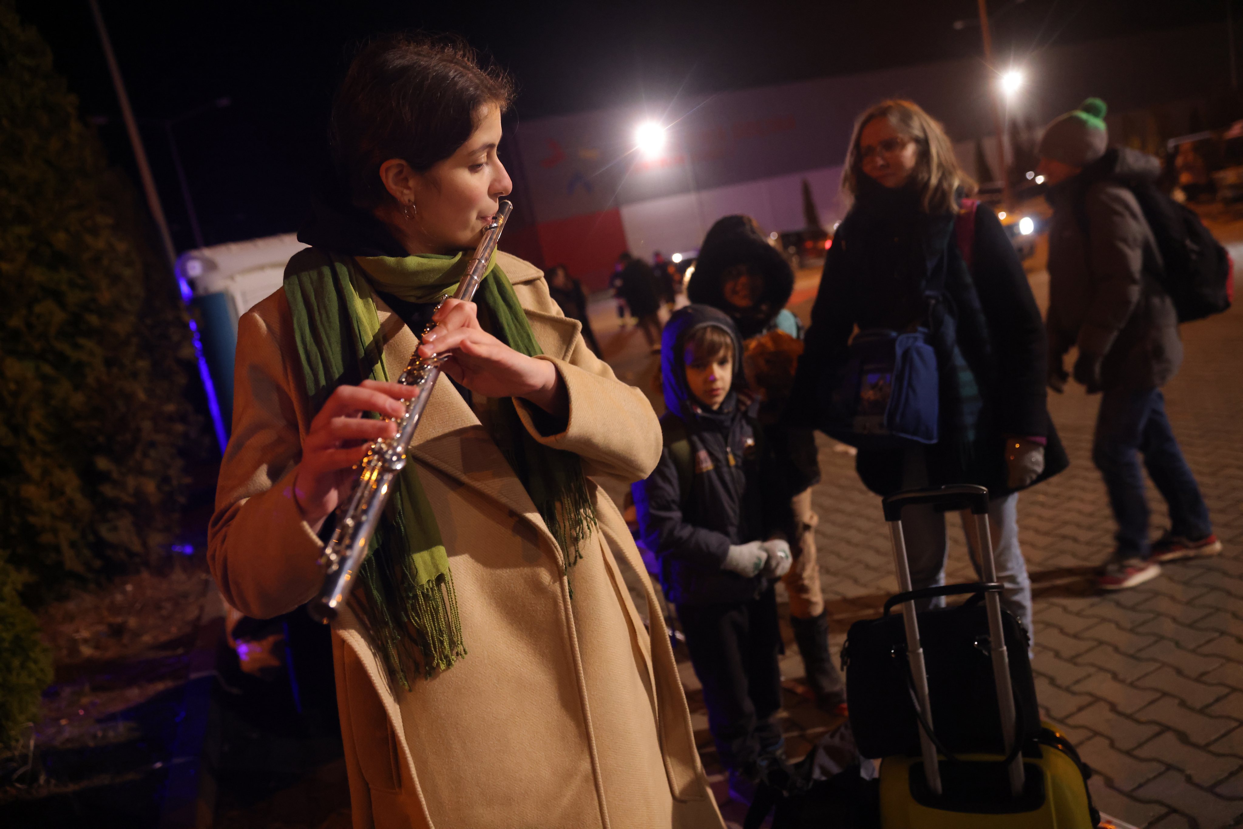 Nadiya Khmelenko, de 17 anos, toca música clássica na sua flauta enquanto espera, com os pais e três irmãos, por transporte na fronteira polaca