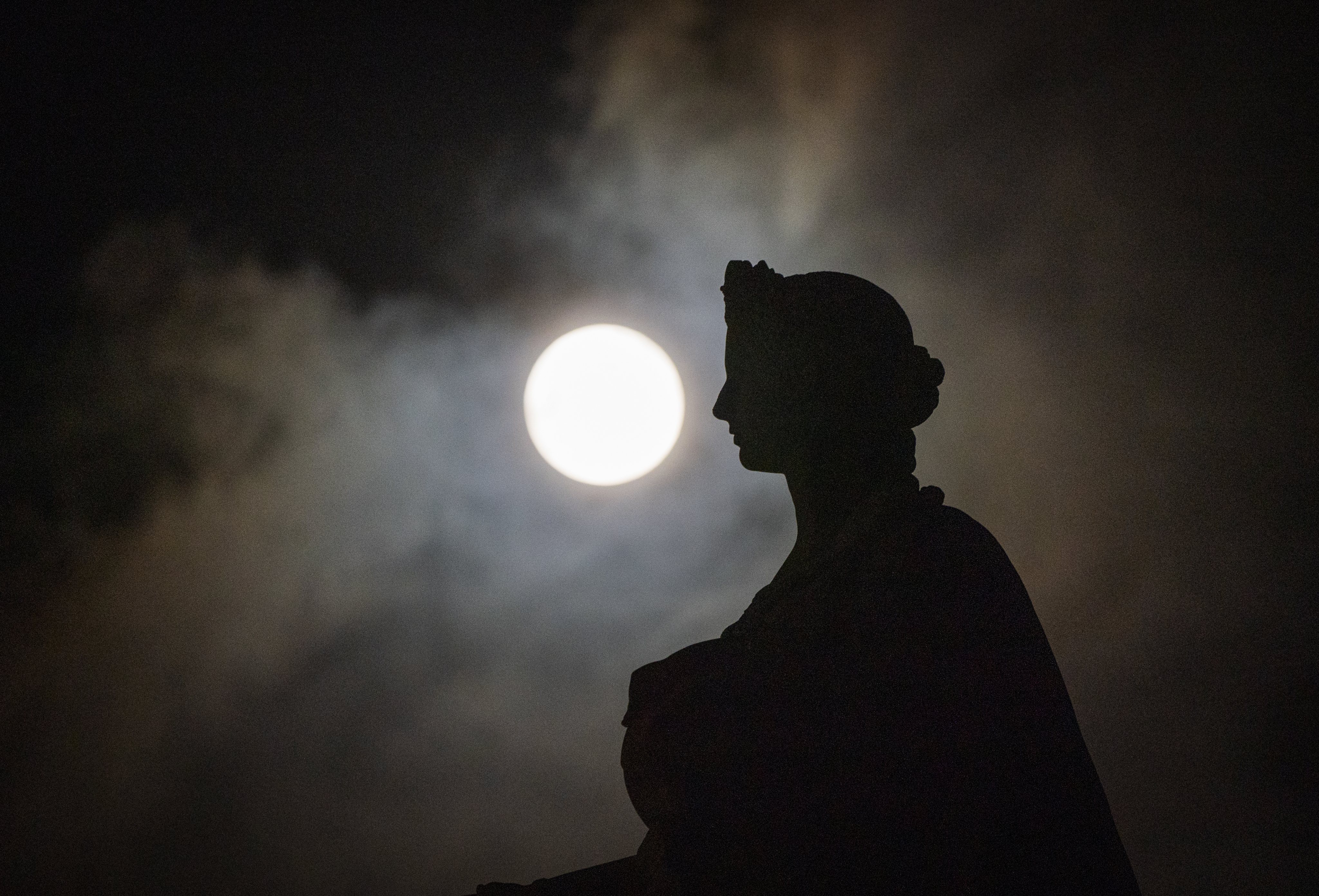 A Lua de Neve atrás da estátua da Rainha Vitória, na Academia Real Escocesa, em Edimburgo