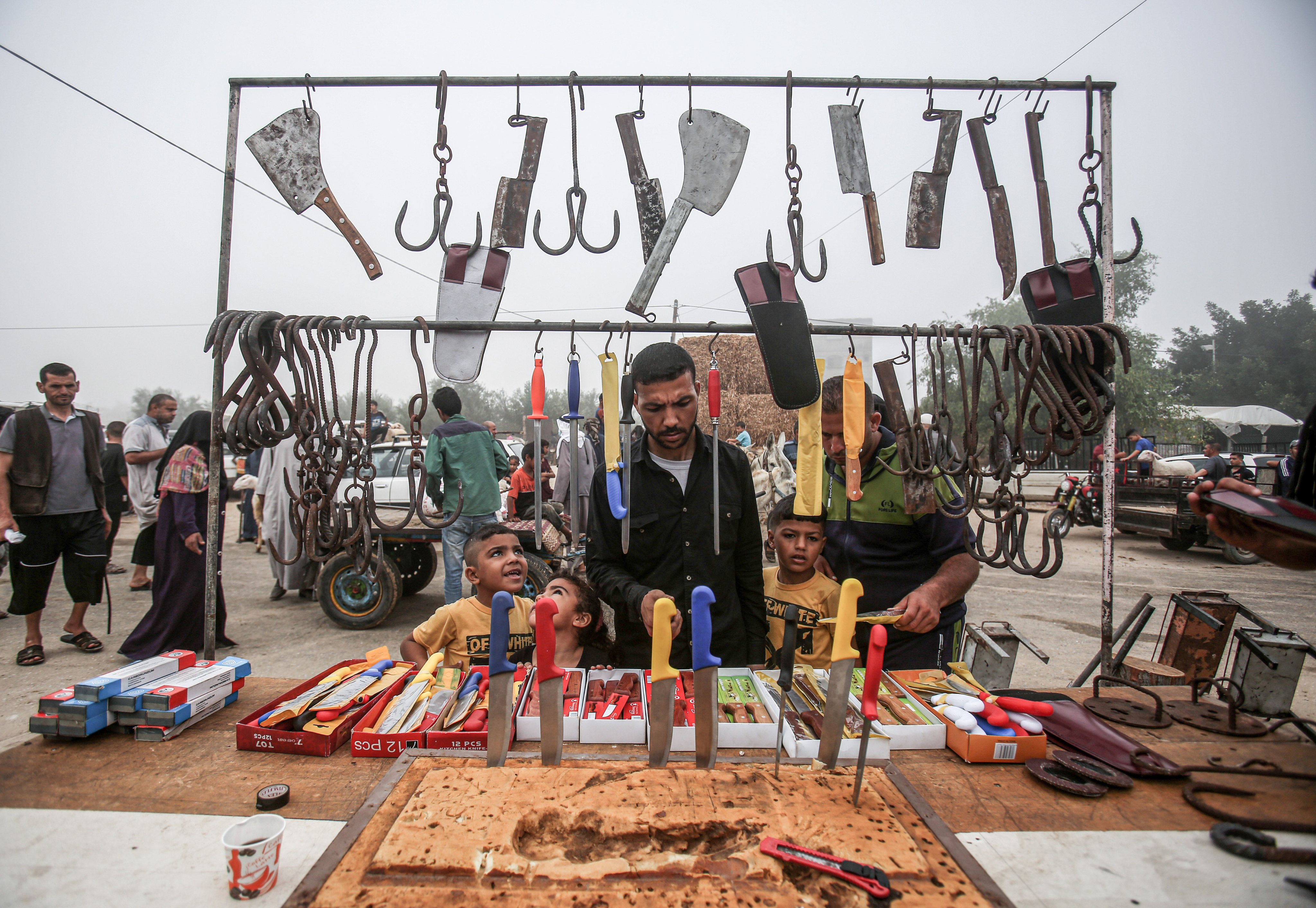 Palestinians buy sharp cutting pieces sold by a vendor at