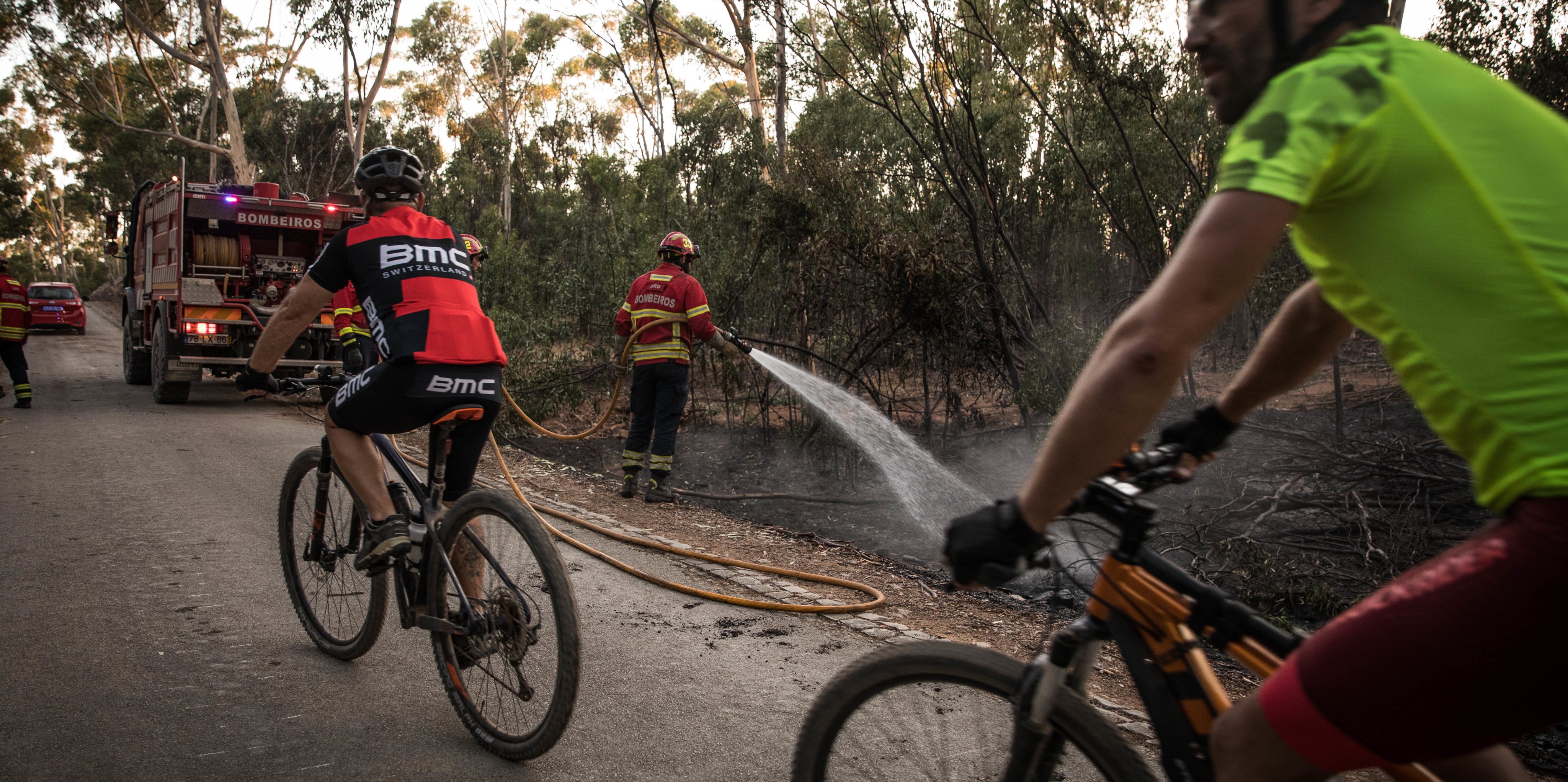 Dois ciclistas passeiam enquanto os bombeiros procediam às fases de consolidação do incêndio para evitar novos reacendimentos.