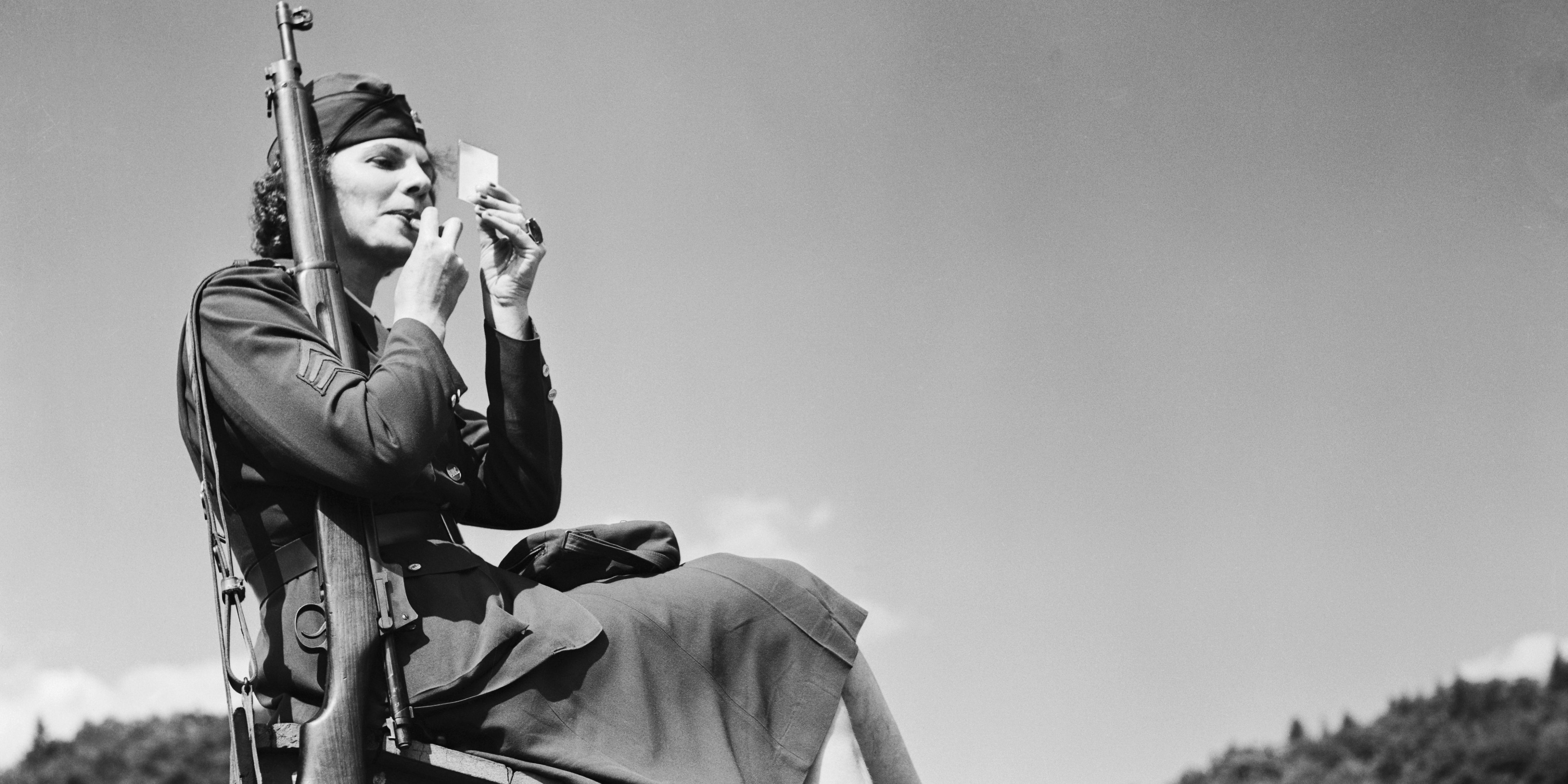 Woman Soldier Sitting and Applying Lipstick to Her Face