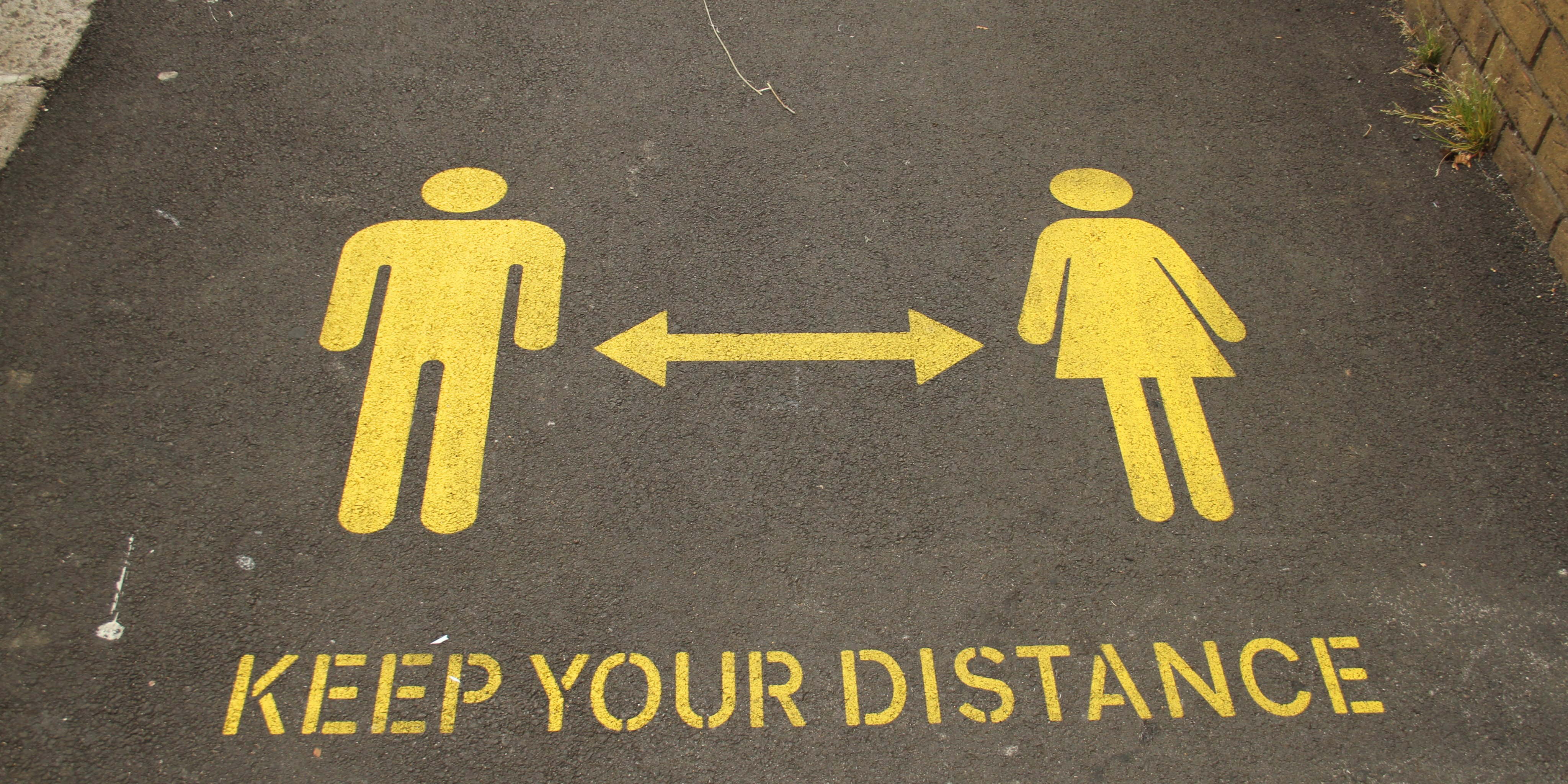 A view of a Social distancing sign stencilled on a footpath
