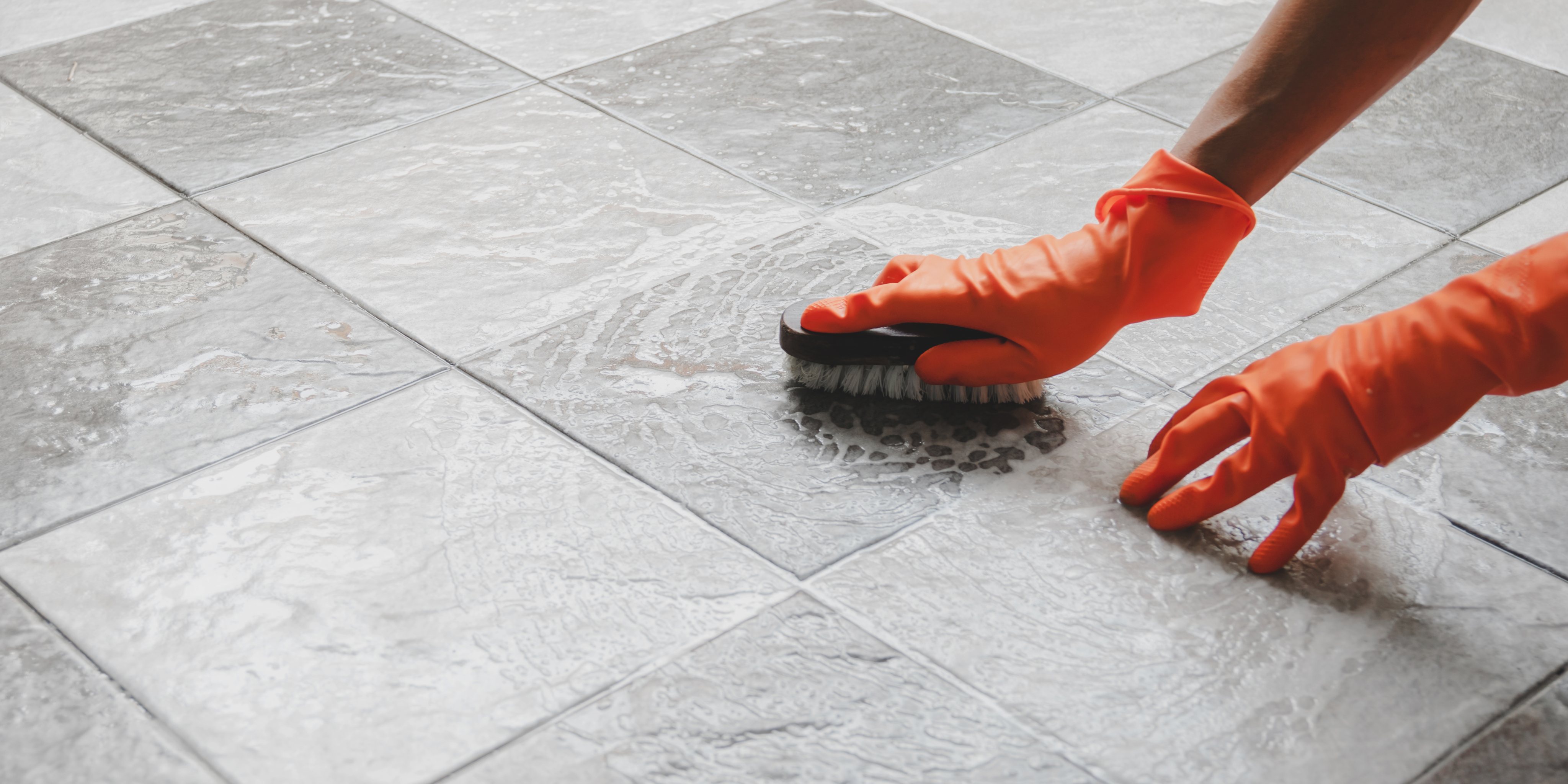 Cropped hands cleaning tiled floor