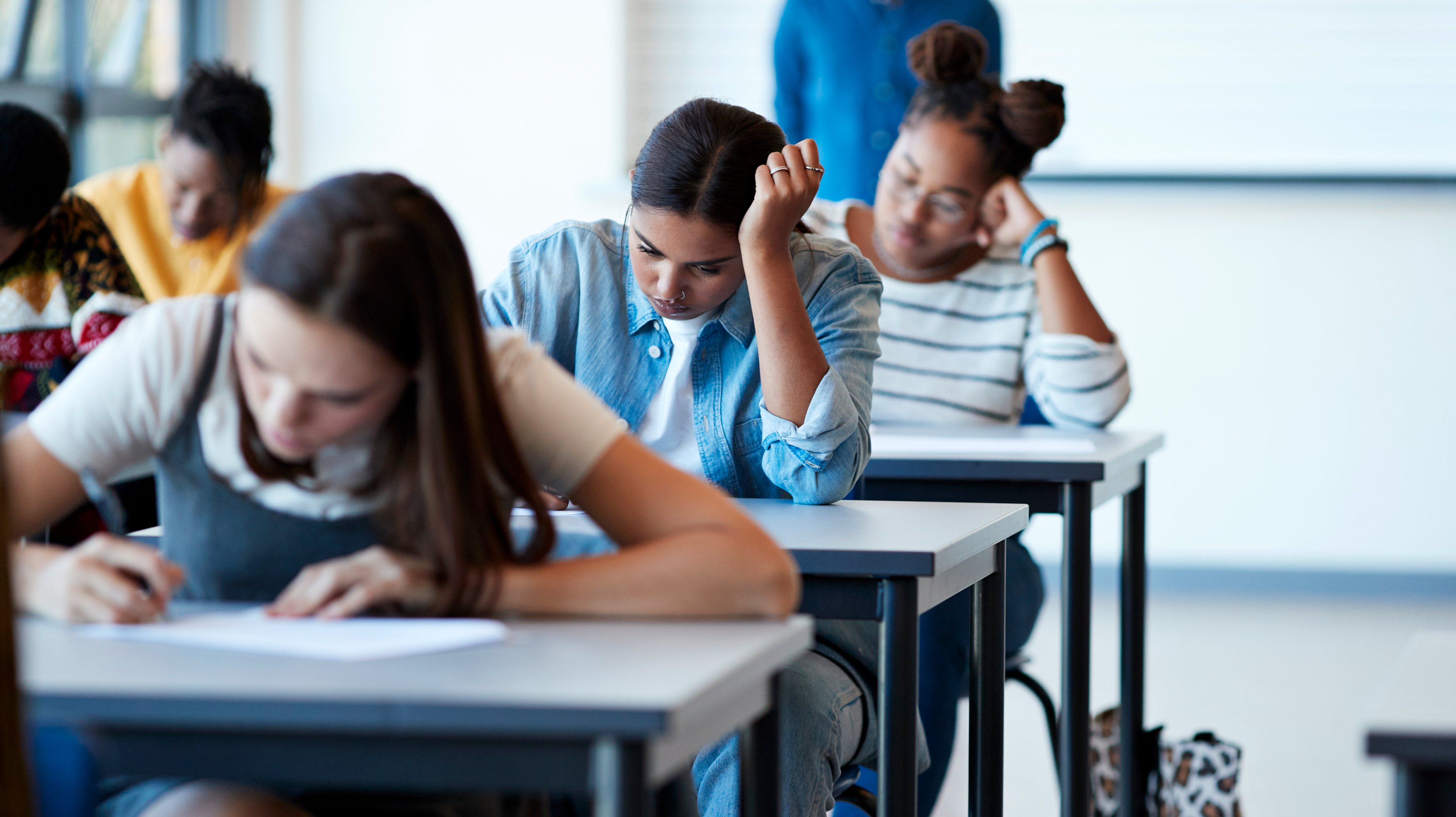 Young multi-ethnic female students writing exams
