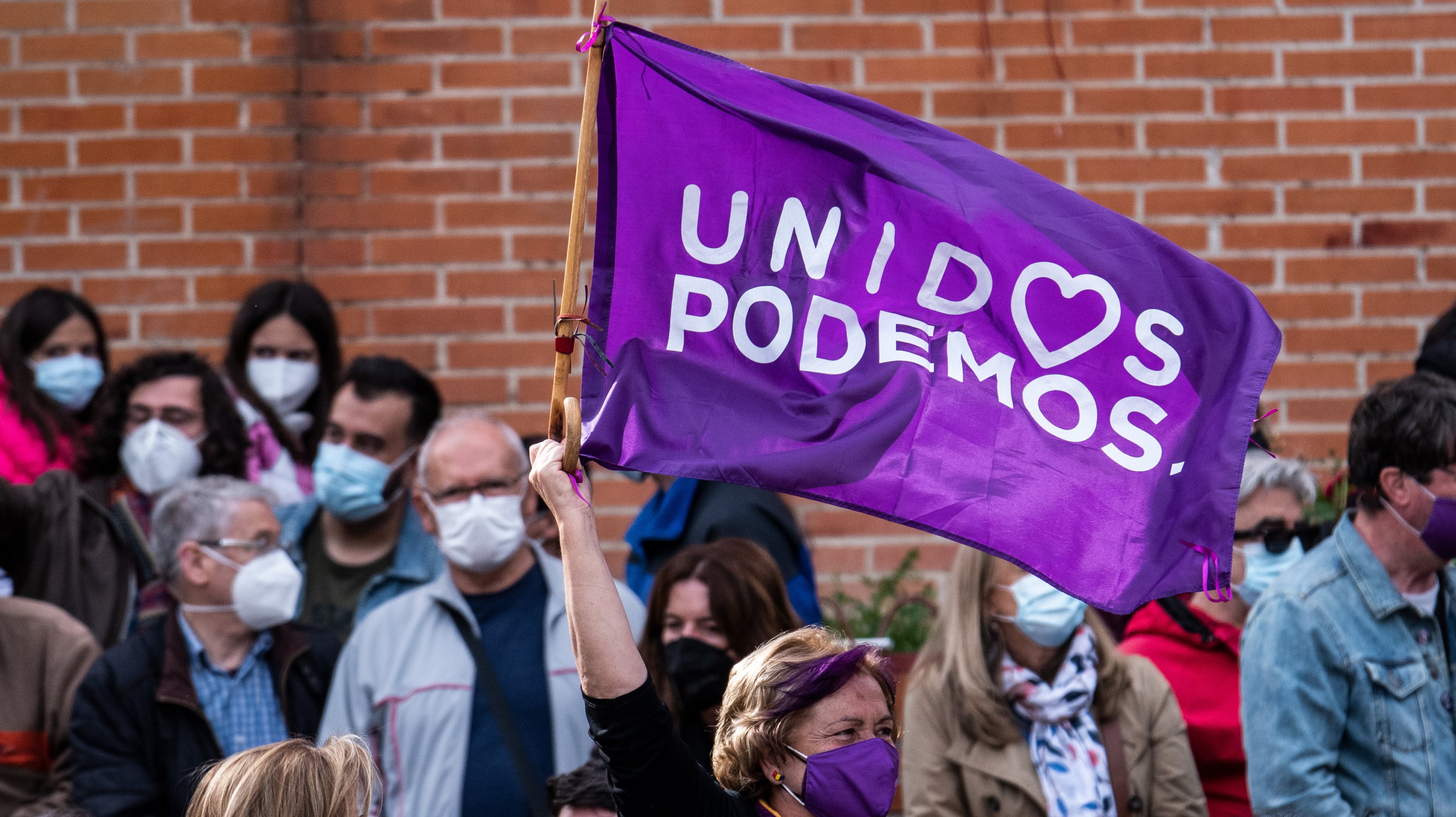 A woman waving a flag during a rally of Unidas Podemos party